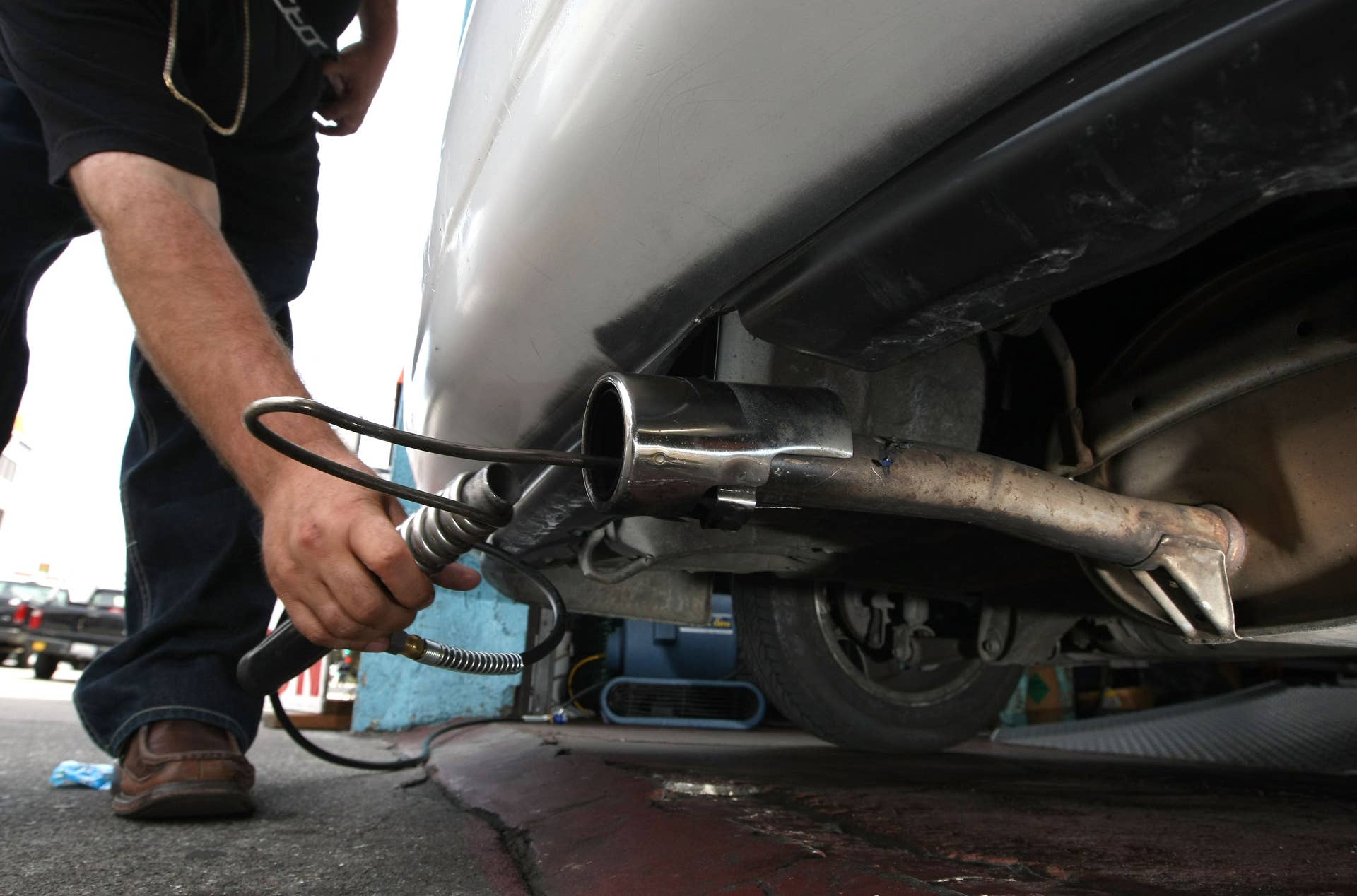 Thomas Zielin inserts a probe into the tailpipe of a car while performing an emissions test at Smog Queen May 18, 2009 in San Francisco, California.