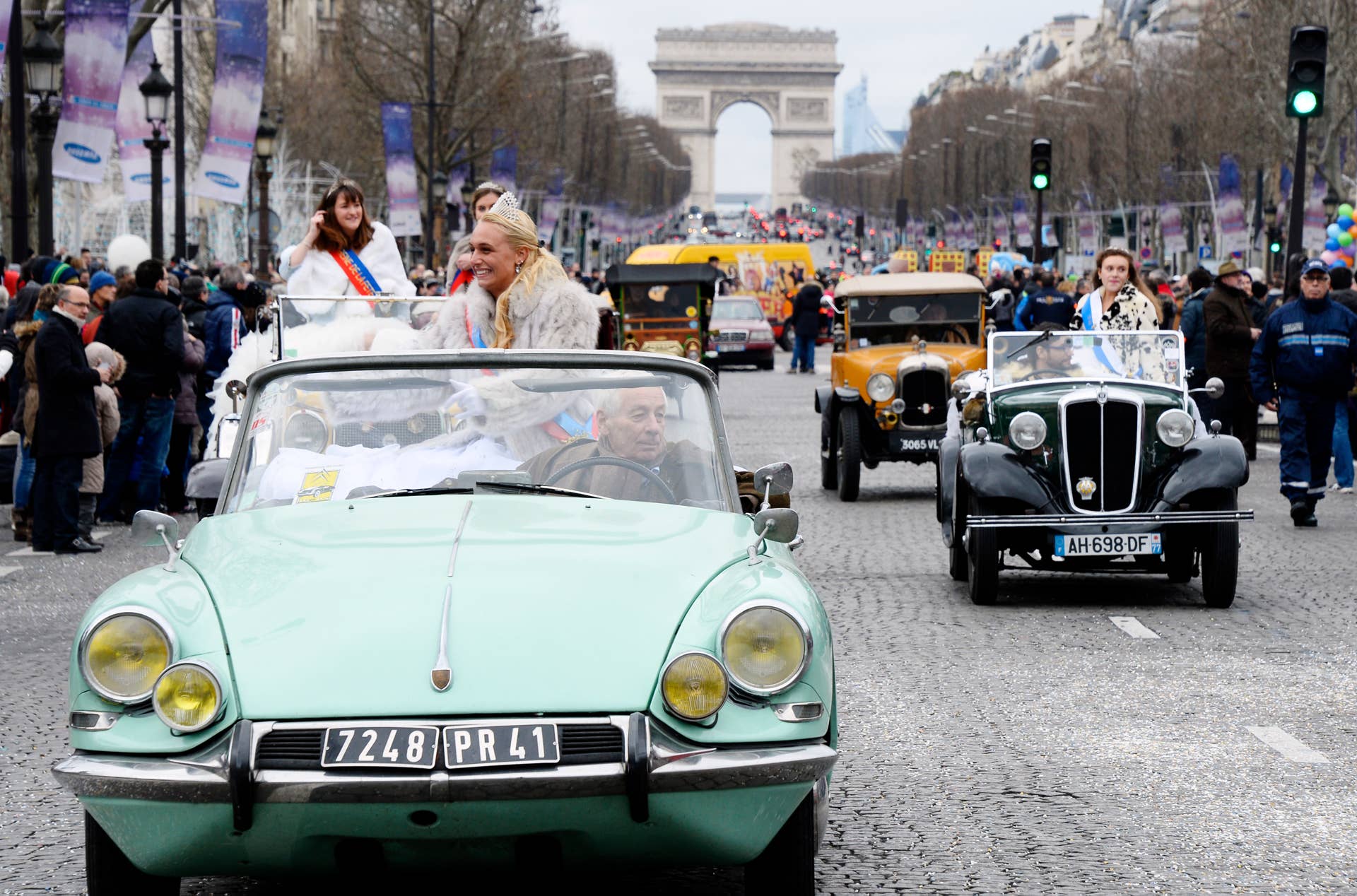 People look at a French Citroen DS car and other vintage cars during the parade organized by French circuses on January 1, 2014 on the Champs-Elysees in Paris to celebrate the New Year. At background, the Arc de triomphe (Triumph arch). AFP PHOTO BERTRAND GUAY (Photo credit should read BERTRAND GUAY/AFP/Getty Images)