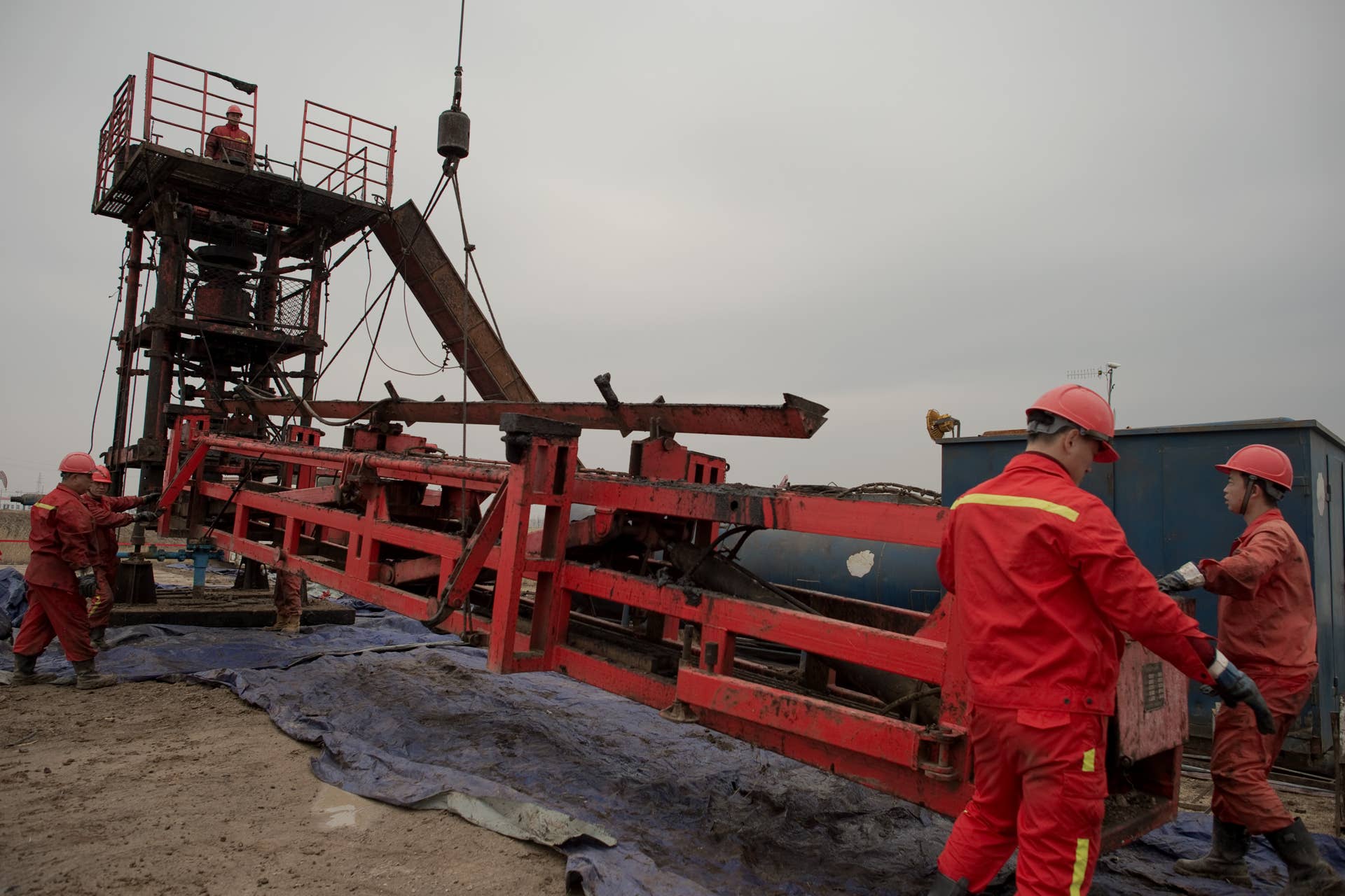 This picture taken on May 2, 2016 shows workers constructing an oil rig in Daqing, Heilongjiang province. Once the pride of Communist rulers and now hit by a global glut and slowing domestic growth, China's largest oilfield epitomises Beijing's reluctance to cut jobs at loss-making state-run operations. Thousands of oil pumps painted black, yellow and red stretch to the horizon in Daqing, which has produced more than two billion tonnes of the black gold since it started flowing almost 60 years ago. / AFP / NICOLAS ASFOURI / TO GO WITH AFP STORY CHINA-ECONOMY-OIL-POLITICS BY TOM HANCOCK (Photo credit should read NICOLAS ASFOURI/AFP/Getty Images)