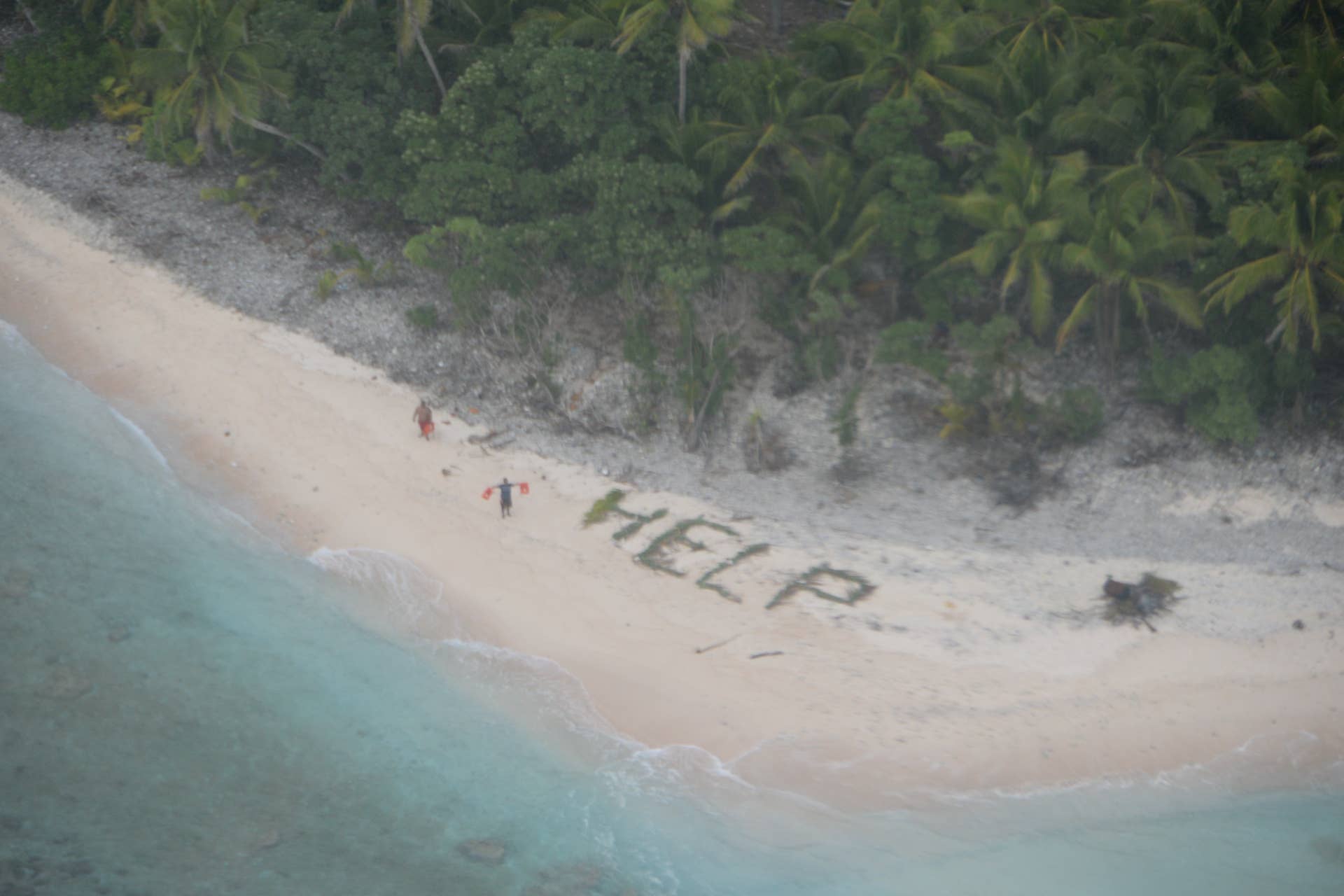 160407-N-ZZ999-004 FANADIK, Micronesia (April 7, 2016) Two men wave life jackets and look on as a U.S. Navy P-8A maritime surveillance aircraft discovers them on the uninhabited island of Fanadik. Three days earlier, the three's 19-foot skiff capsized after setting out to sea from Pulap, FSM. The P-8A, attached to Patrol Squadron (VP) 5, and operating from Misawa, Japan, responded to a call for assistance from the U.S. Coast Guard and located the men as they waved life jackets and stood next to a large "help" sign made of palm leaves. The men reported their vessel was capsized by a large wave a few hours after their departure on April 4, and spent the night swimming until they arrived at Fandadik Island, approximately four nautical miles from Pulap. A small boat from Pulap recovered the men from the island with no reported injuries. VP-5 is in the midst of a routine deployment to the U.S. 7th Fleet area of operations. (U.S. Navy photo by Ensign John Knight/Released)