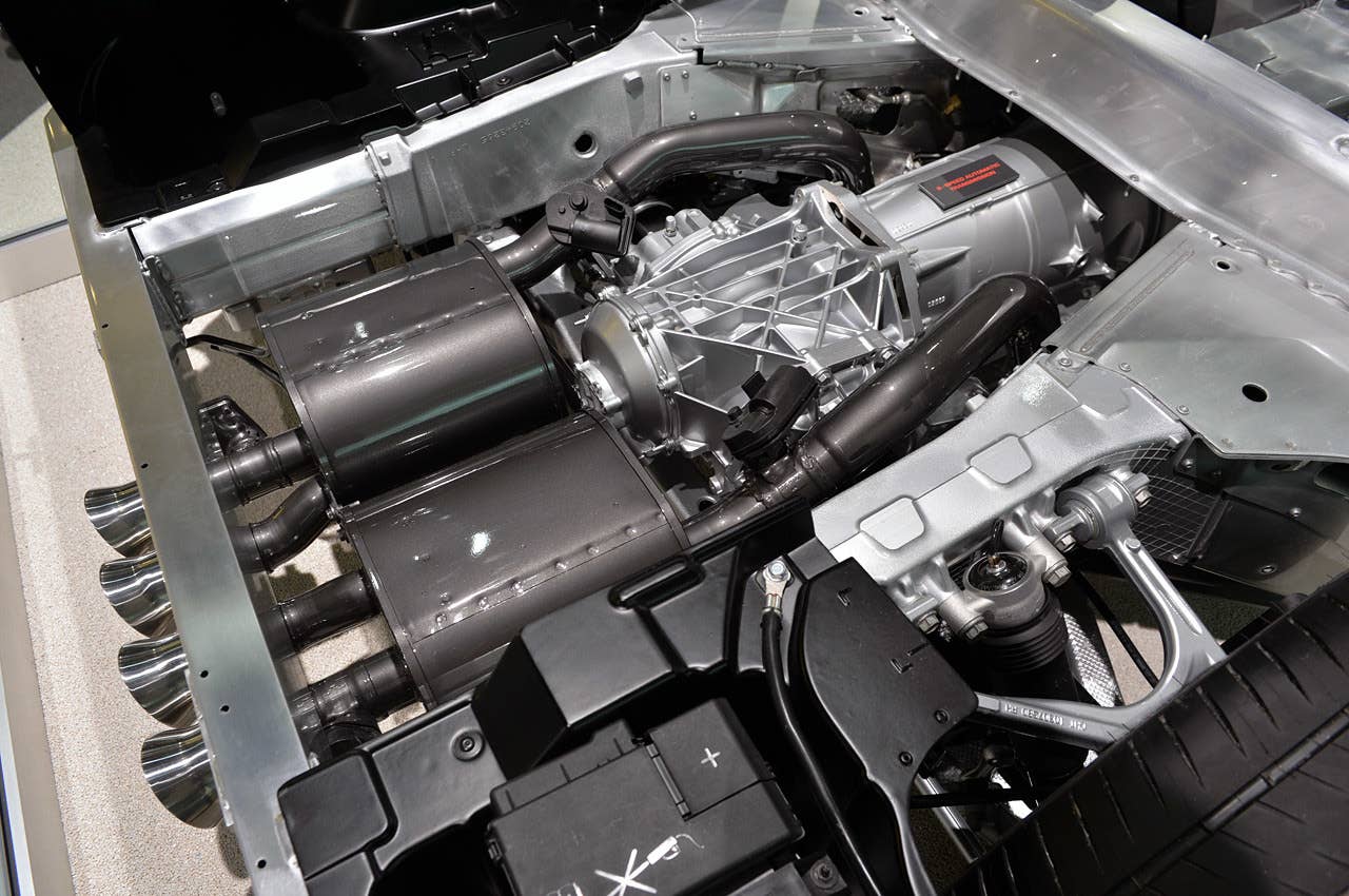 This view, standing directly over the battery box, allows a clean view of the exhaust system as it works its way around the transmission and differential. Note the servo-operated flappers in the exhaust tubes, just aft of the axles, which control the flow of hot gasses. There are more flappers on on the outboard exhaust tips, also visible in the pictures. Lastly, this image clearly shows the cast aluminum frame holding the upper control arms and top of the Magnetic Selective Ride Control unit.