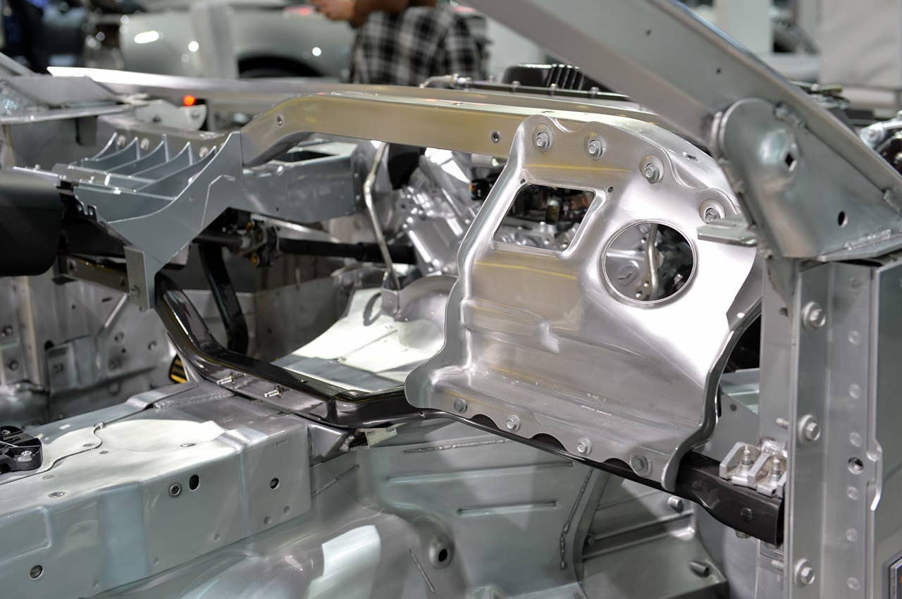 Peering at the aluminum surrounding the compartment that will contain the large passenger-side airbag. A structural steel box-shaped pipe runs beneath the dashboard (some of the only steel in the Z06) because of packaging limitations. Note how it bolts into place on a welded bracket at the base of the A-pillar.