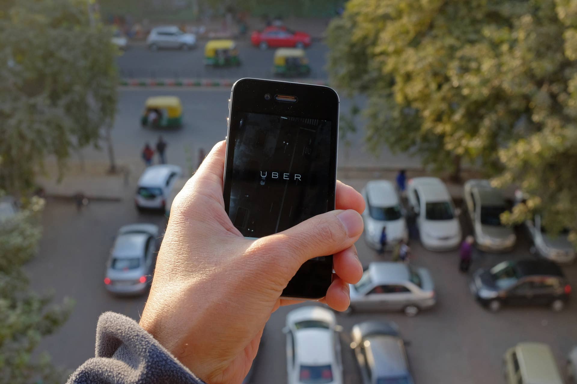 The Uber smartphone app, used to book taxis using its service, is pictured over a parking lot as auto-rickshaws (background) ply a road in the Indian capital New Delhi on December 7, 2014. An Uber taxi driver allegedly raped a 25-year-old passenger in the Indian capital before threatening to kill her, police said December 7, in a blow to the company's safety-conscious image. AFP PHOTO/TENGKU BAHAR        (Photo credit should read TENGKU BAHAR/AFP/Getty Images)