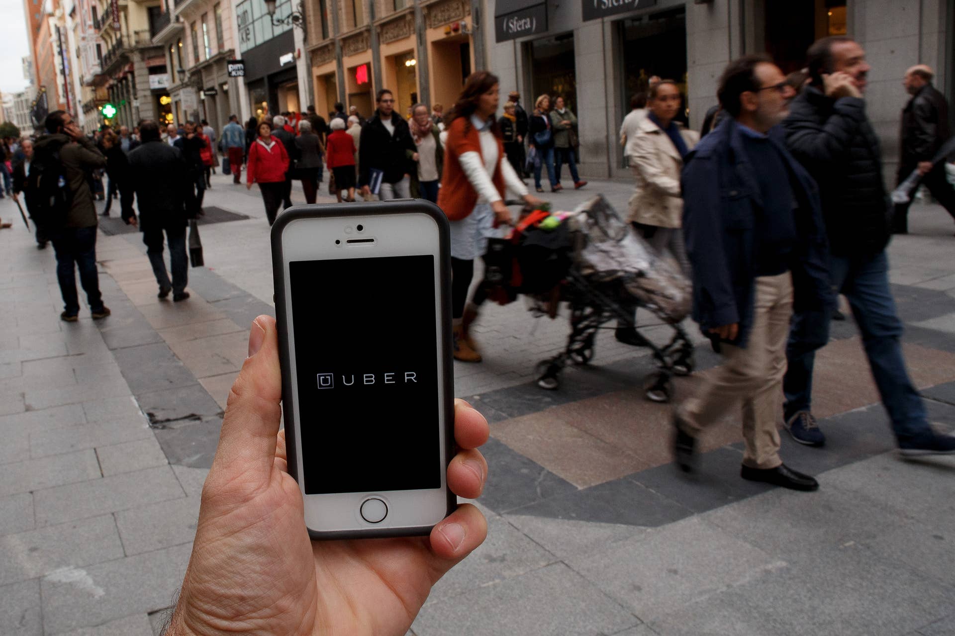 MADRID, SPAIN - OCTOBER 14:  In this Photo Illustration a smart phone displays a picture with the logo of the news taxi app 'Uber' as people walk past on October 14, 2014 in Madrid, Spain. 'Uber' application started to operate in Madrid last September despite Taxi drivers claim it is an illegal activity and its drivers currently operate without a license. 'Uber' is an American based company which is quickly expanding to some of the main cities from around the world.  (Photo Illustration by Pablo Blazquez Dominguez/Getty Images)