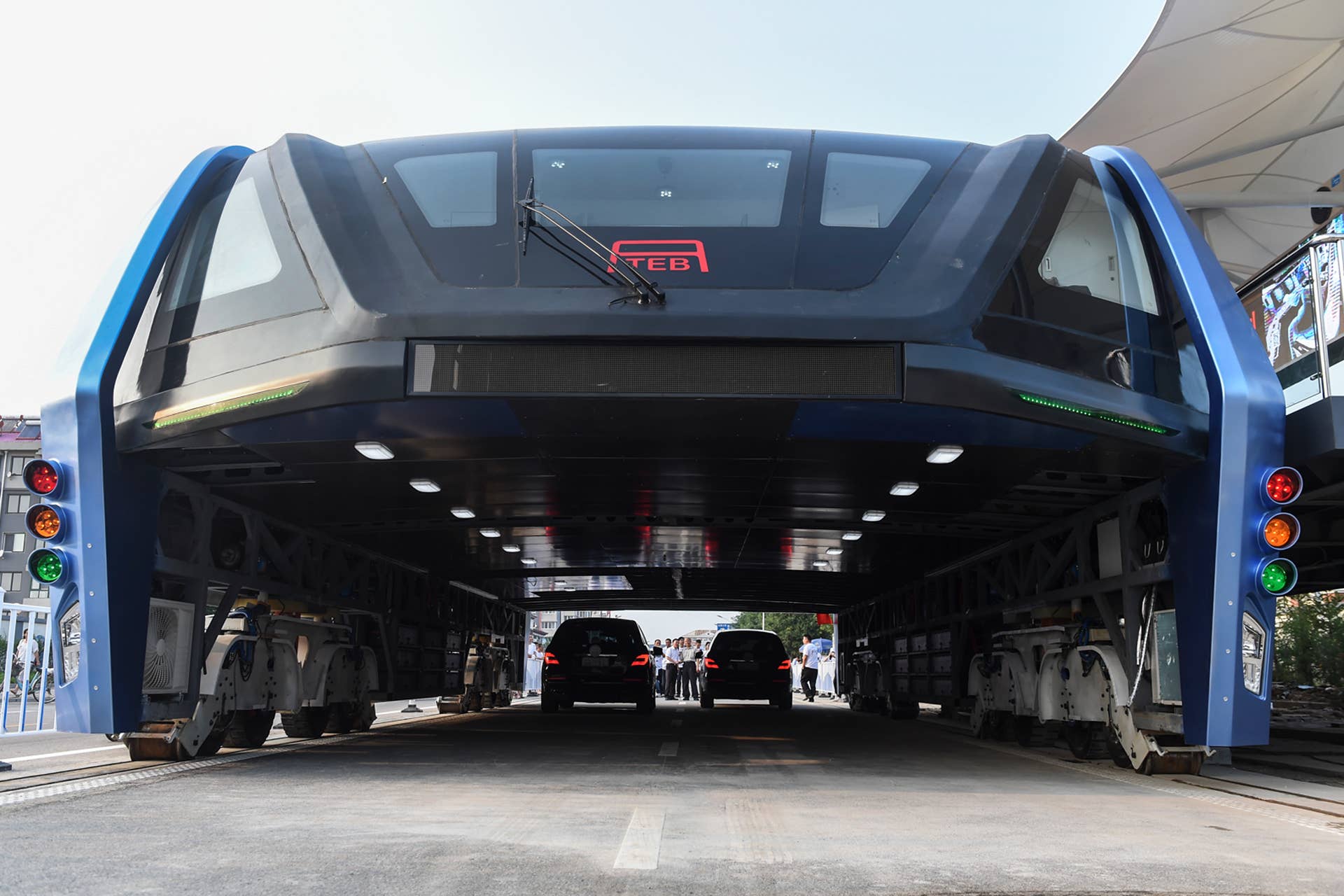 In this Tuesday, Aug. 2, 2016 photo released by Xinhua News Agency, people look at the Transit Elevated Bus TEB-1 run past vehicles as they conducted a test run in Qinhuangdao, north China's Hebei Province. The 72-feet long and 25-feet wide Transit Elevated Bus (TEB) powered by electricity can carry more than hundreds passengers, is designed to go over the normal traffic to help ease traffic congestion without having to dig new tunnels or build elevated rail tracks. (Luo Xiaoguang/Xinhua via AP)