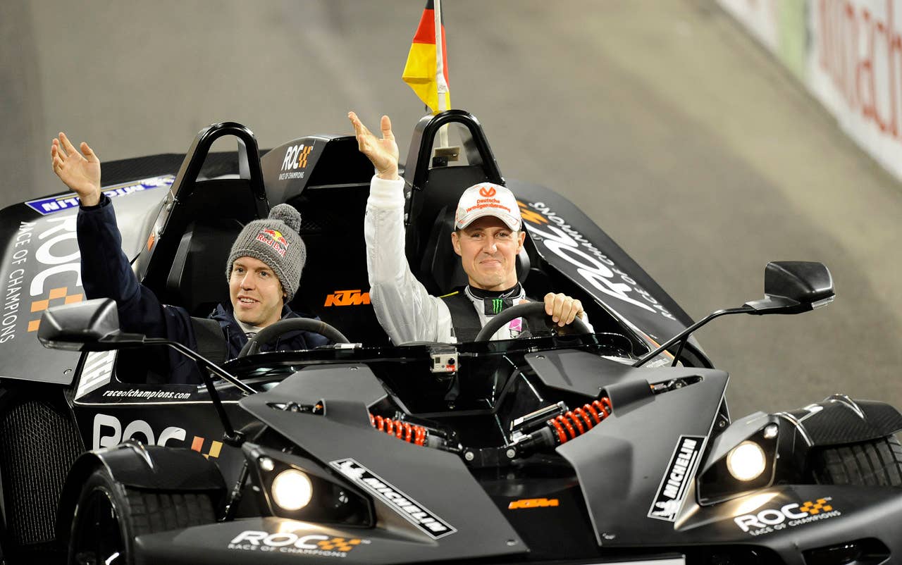 Germany's Red Bull F1 World champion Sebastian Vettel, left, and teammate F1 legend Michael Schumacher react to supporters during the Race of Champions at the arena in Duesseldorf, western Germany, Saturday, Dec. 3, 2011.(AP Photo/Martin Meissner)