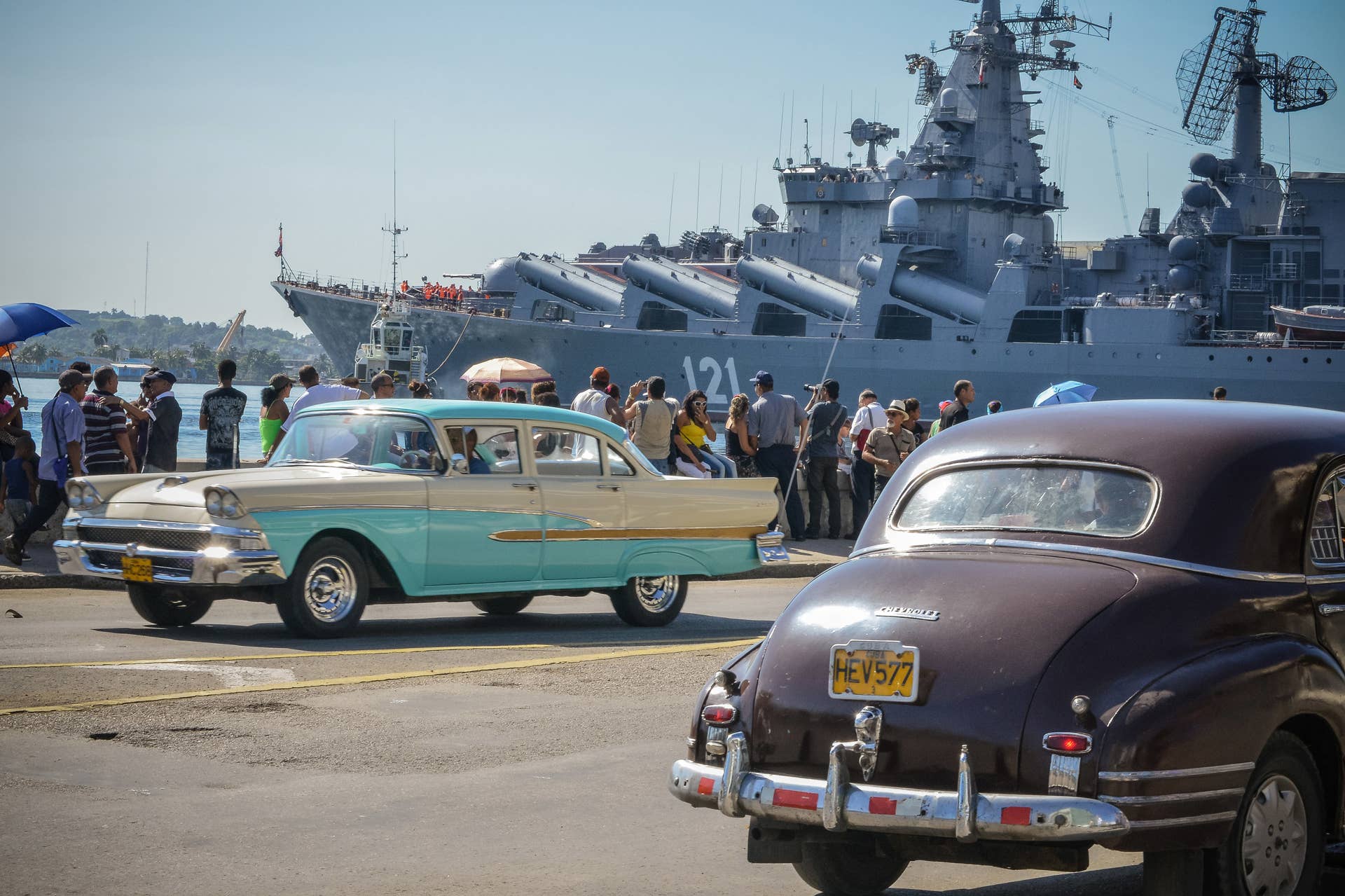 Vintage US-made cars pass by as Cubans watcht the 'Moskva' Russian guide missile cruiser arriving at Havana's harbour, on August 3, 2013. The vessel is part of a three-ship group  in official visit to Cuba. AFP PHOTO/Adalberto ROQUE        (Photo credit should read ADALBERTO ROQUE/AFP/Getty Images)