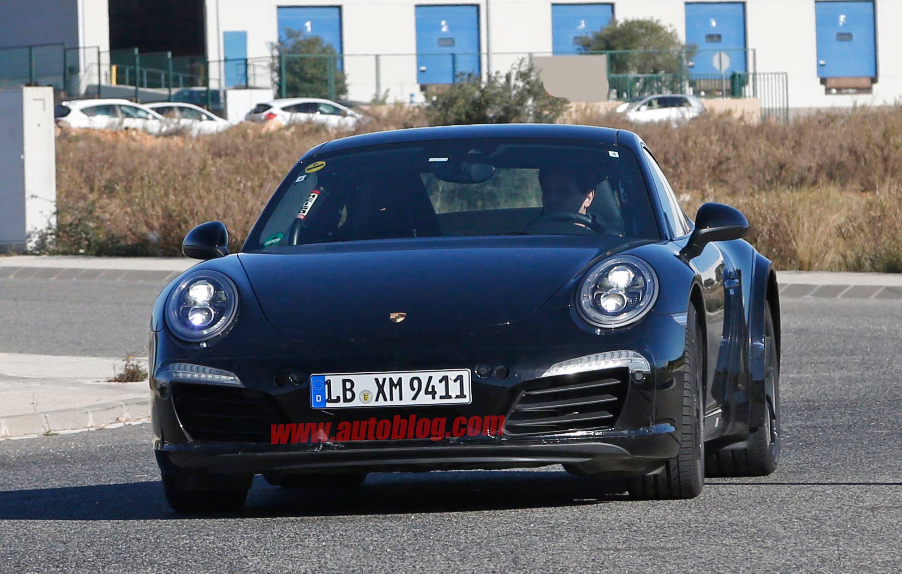 Spy shot of the next-generation 992-model Porsche 911 thought to hide a hybrid powertrain, front view.