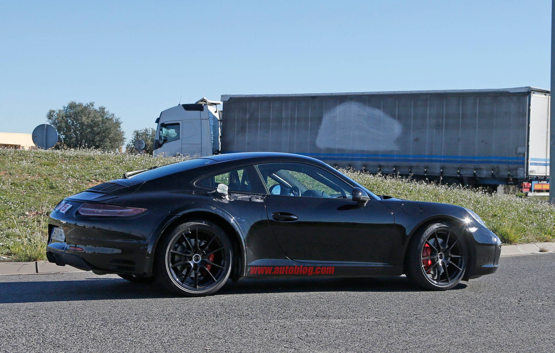 Spy shot of the next-generation 992-model Porsche 911 thought to hide a hybrid powertrain, side.