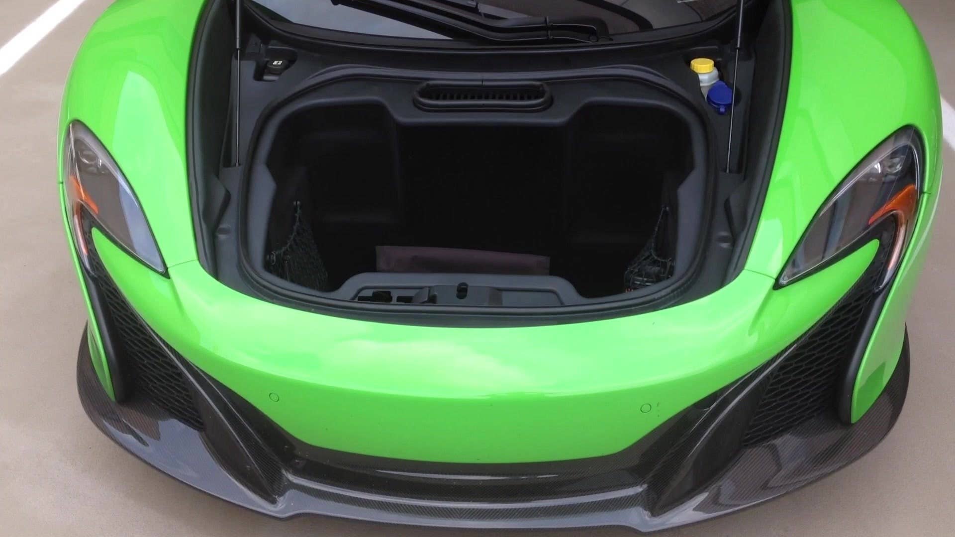 Senior editor Greg Migliore shows off the trunk compartment in the 2015 McLaren 650S.
