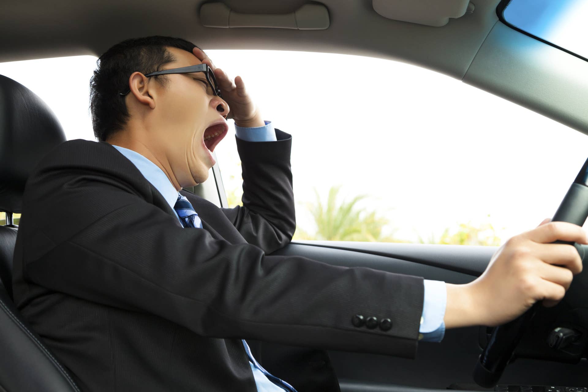 Asian Exhausted driver yawning and driving car