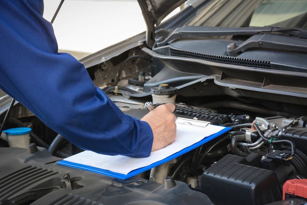 Auto mechanic (or technician) checking car engine at the garage