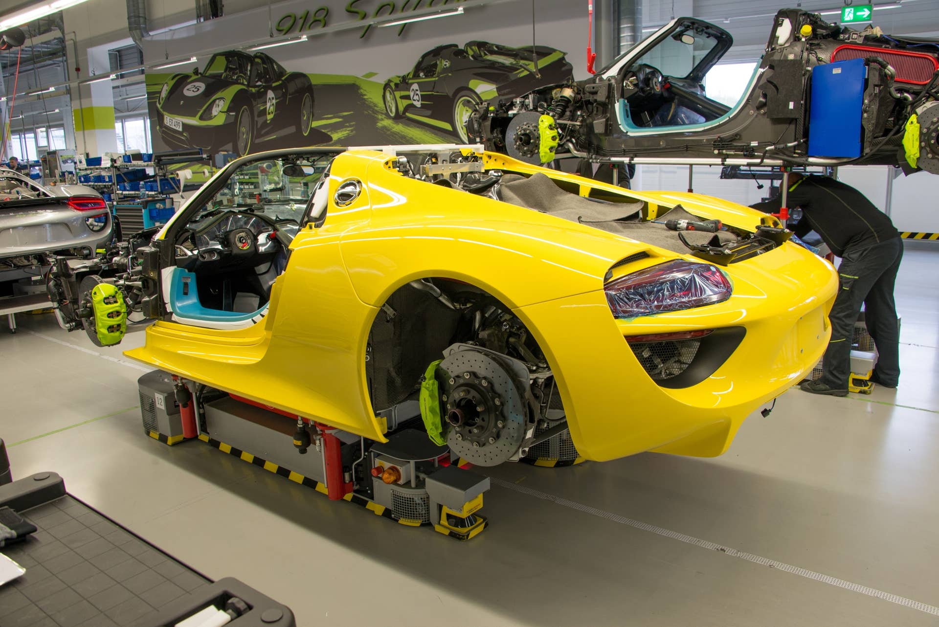 This yellow 918 (the only one of its color in the building) is being prepared for its rear wing and other body panels. Porsche has special floor jacks, which bolt onto the single lug hubs, to allow the suspension to support the weight of the vehicle as the panels are precisely fit by hand.  Each of the vehicles on the assembly line has a VIN, but they are not sequential as customers have made special requests for specific numbers out of order.