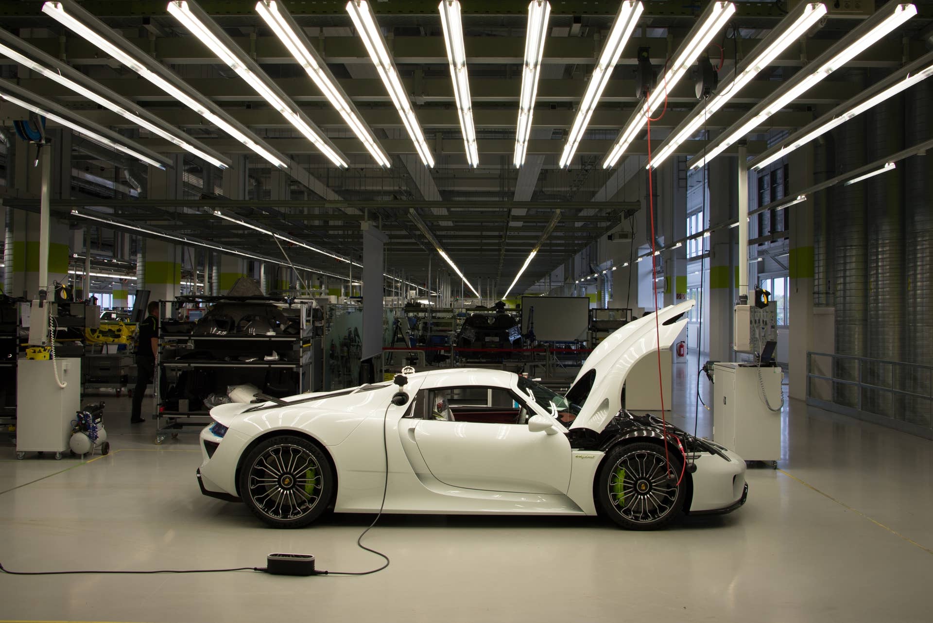 The completed 918 Spyder rests under special fluorescent lights for its final inspection before leaving the assembly floor — an event that happens up to four times per day. There is no fuel in its gasoline tank, which would prevent it from operating on public roads, but special software allows its electric motors to power — silently — out of the building.  With the entire production run now spoken for, Porsche estimates that the last 918 Spyder will roll out of the assembly plant in July of 2015.