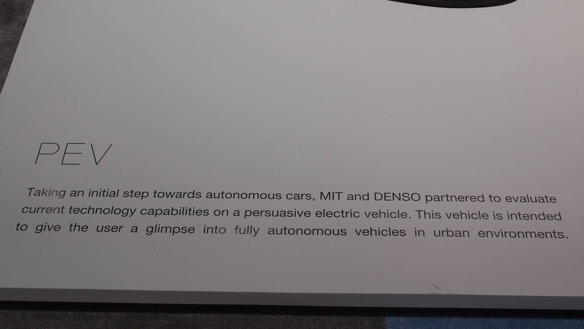 Persuasive Electric Vehicle (PEV) information plaque: "Taking an initial step towards autonomous cars, MIT and DENSO partnered to evaluate current technology capabilities on a persuasive electric vehicle. This vehicle is intended to give the user a glimpse into fully autonomous vehicles in urban environments."