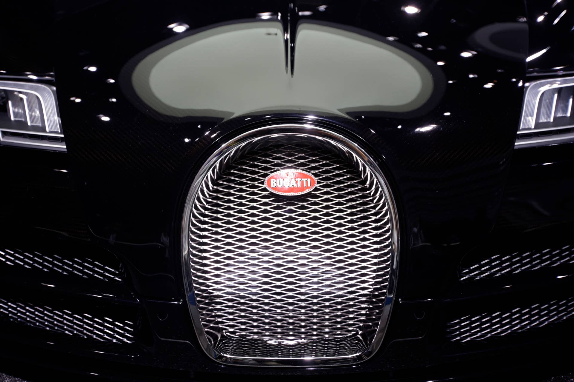 A logo sits on the front grill of a Bugatti Veyron automobile, produced by Volkswagen AG, at the 65th Frankfurt International Motor Show in Frankfurt, Germany, on Tuesday, Sept. 10, 2013. The 65th Frankfurt International Motor Show, Europe's biggest auto event will open to the public on Sept. 12 and showcase the industry's latest models. Photographer: Jason Alden/Bloomberg via Getty Images