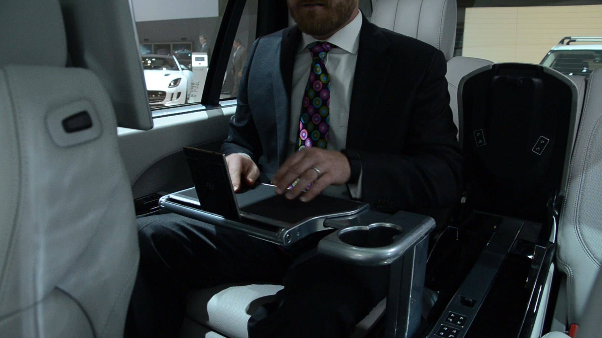 Autoblog's Mike Austin demonstrates the electrically deployable tray tables in the back of the Range Rover SV Autobiography