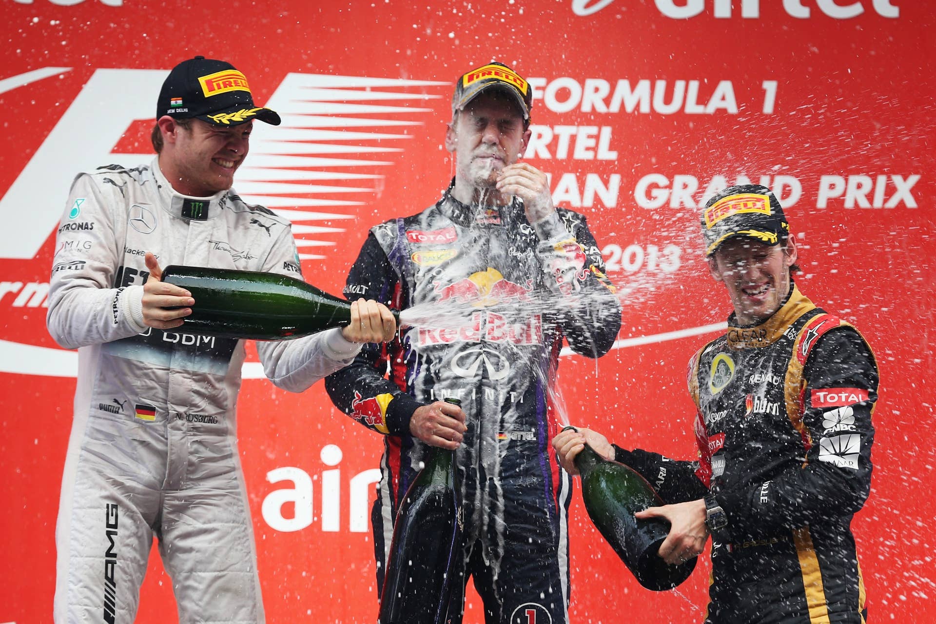 NOIDA, INDIA - OCTOBER 27:  Race winner and 2013 Formula One World Champion Sebastian Vettel (C) of Germany and Infiniti Red Bull Racing celebrates with second placed Nico Rosberg (L) of Germany and Mercedes GP and third placed Romain Grosjean (R) of France and Lotus on the podium following the Indian Formula One Grand Prix at Buddh International Circuit on October 27, 2013 in Noida, India.  (Photo by Mark Thompson/Getty Images)