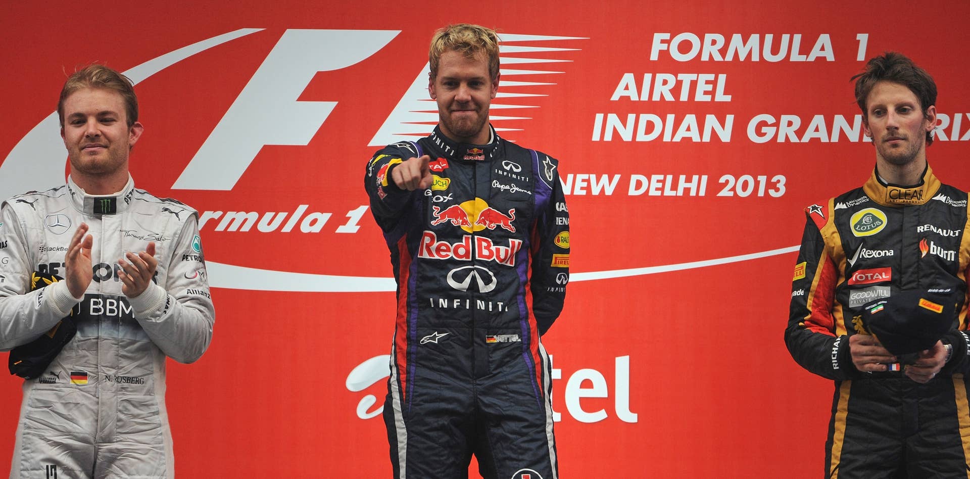 Red Bull driver Sebastian Vettel of Germany (C), flanked by second-placed Mercedes driver Nico Rosberg of Germany (L) and third-placed Lotus driver Romain Grosjean of France (R), celebrates after winning the Formula One Indian Grand Prix 2013 at the Buddh International circuit in Greater Noida, on the outskirts of New Delhi on October 27, 2013.  AFP PHOTO/Indranil MUKHERJEE        (Photo credit should read INDRANIL MUKHERJEE/AFP/Getty Images)