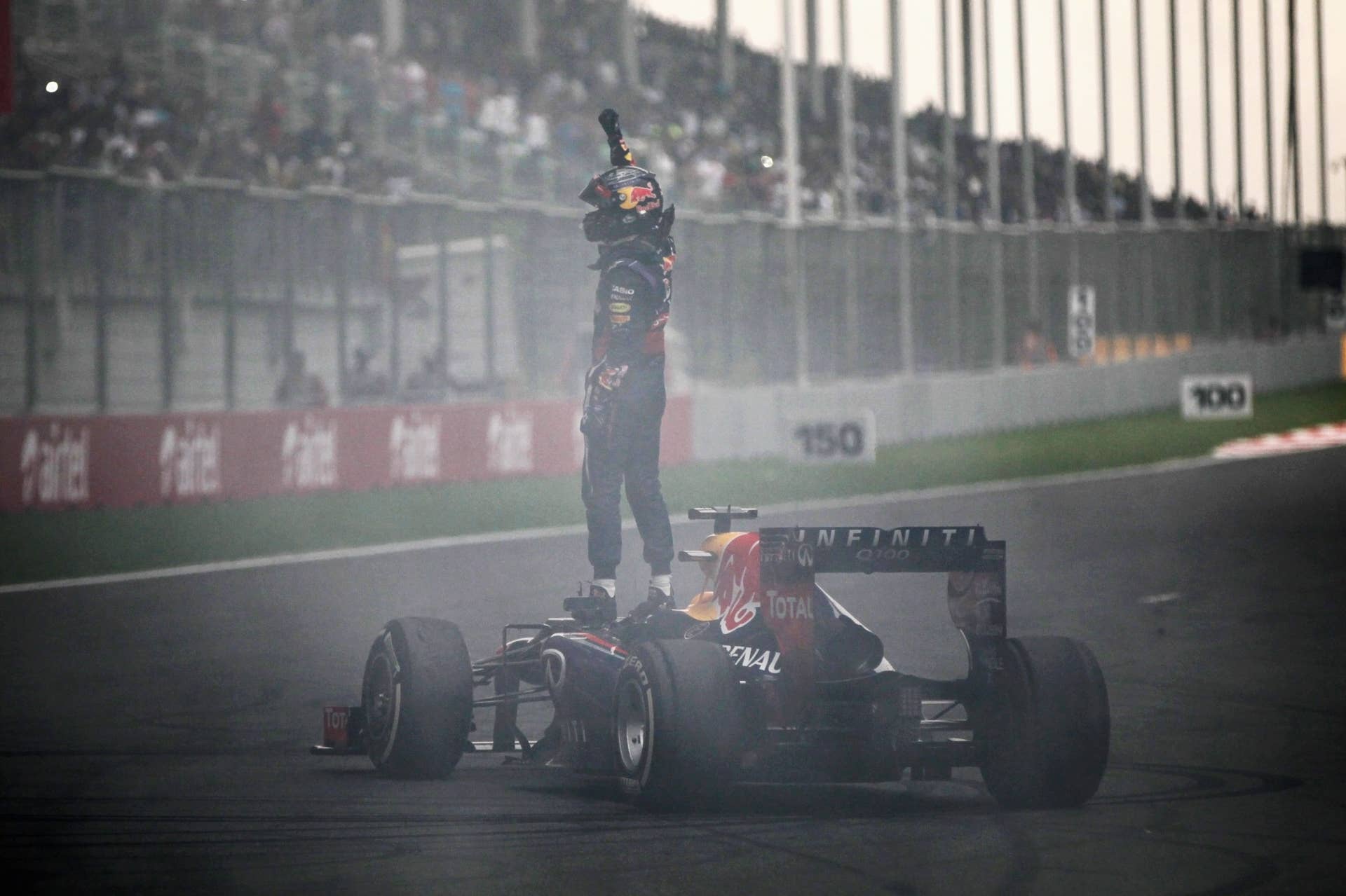 NOIDA, INDIA - OCTOBER 27:  Race winner and 2013 Formula One World Champion Sebastian Vettel of Germany and Infiniti Red Bull Racing celebrates in front of the crowd by doing donuts on the main straight following the Indian Formula One Grand Prix at Buddh International Circuit on October 27, 2013 in Noida, India.  (Photo by Andrew Hone/Getty Images)