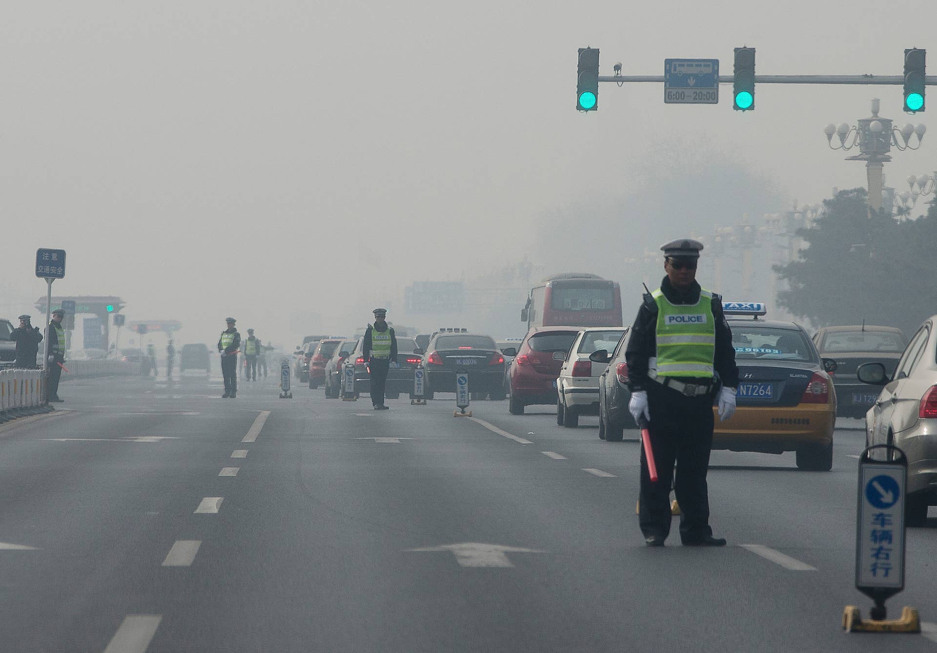 In this Thursday, March 7, 2013 Chinese traffic policemen closed off a road for delegation buses attending the annual Chinese People's Political Consultative Conference held in Beijing, China. Facing public outrage over smog-choked cities and filthy rivers, China's leaders are promising to clean up its neglected environment, a pledge that sets up a clash with political pressures to keep economic growth strong.  (AP Photo/Andy Wong)