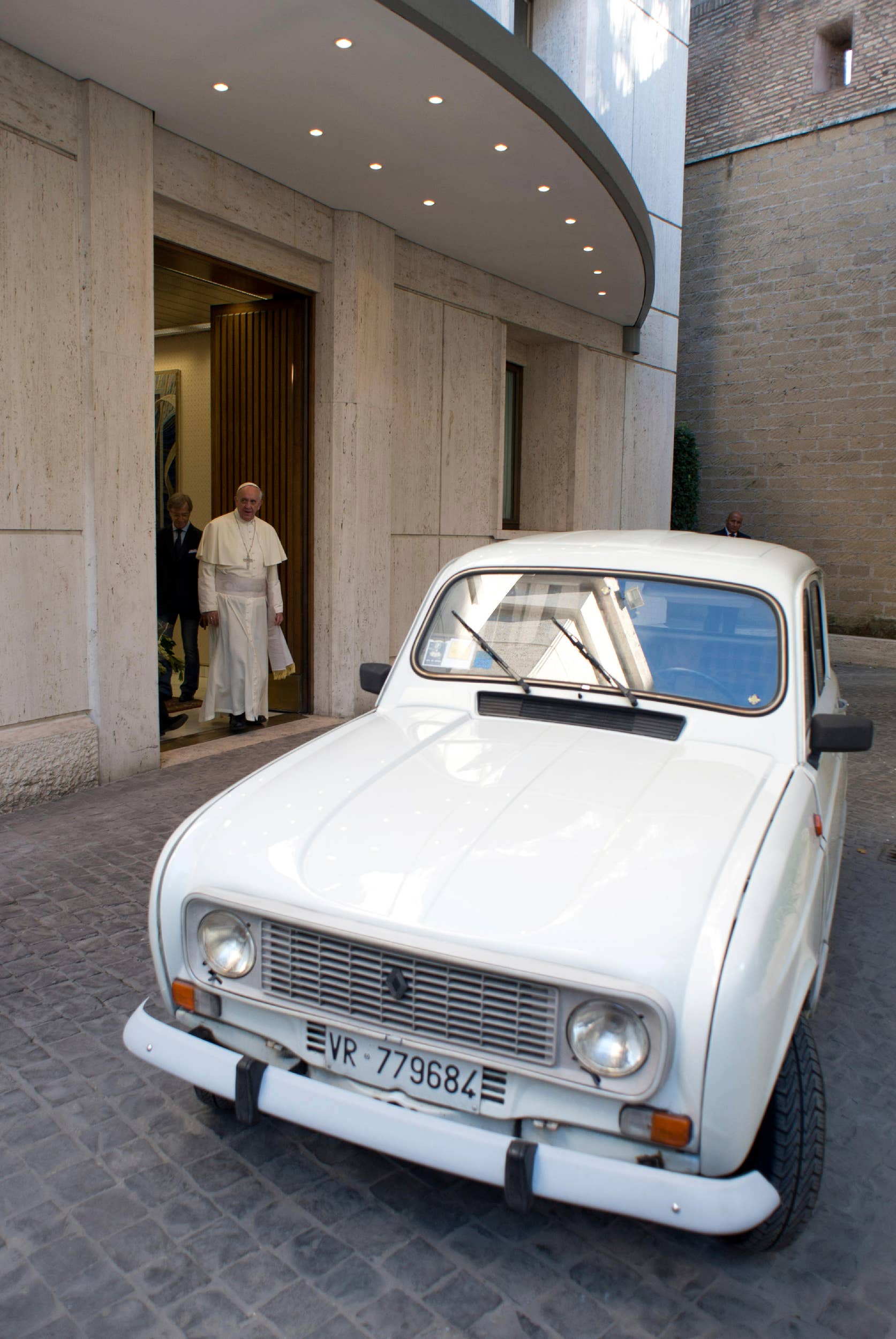 In this Saturday, Sept. 7, 2013 picture made available by the Vatican newspaper l'Osservatore Romano, Pope Francis walks out to look at a Renault 4L donated to him by Rev. Renzo Zocca, parish priest of Santa Lucia di Pescantina, in Verona, northern Italy, at the Vatican. Rev. Zocca, 70, said to the Associated Press Wednesday, Sept. 11, 2013, that he has dedicated his life to helping the needy in the peripheries of Verona, so when he saw that Pope Francis' priority was to reach out to the world's poor and inspire the Catholic leaders to go to slums and peripheries to preach, he decided to donate what he calls his 25-year-old "car of the French farmers" as a symbol of this approach. (AP Photo/L'Osservatore Romano, ho)