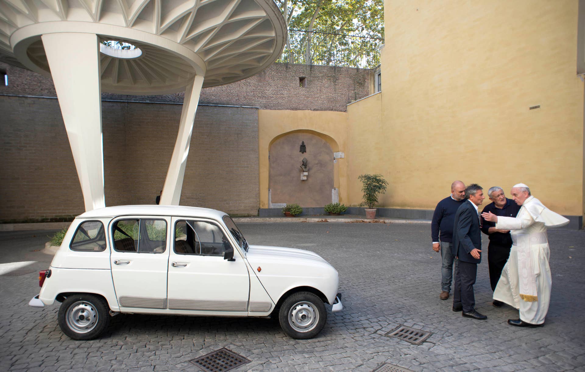 In this Saturday, Sept. 7, 2013 picture made available by the Vatican newspaper l'Osservatore Romano, Pope Francis, right, speaks with Rev. Renzo Zocca, second from right, and owner of the Renault 4L seen at left, his assistant Luigi Macchioni, and car-body repairer Stefano Veronesi, fourth from right, after he was donated the car by Zocca, at the Vatican. Rev. Zocca, 70, told the Associated Press Wednesday, Sept. 11, 2013, that he has dedicated his life to helping the needy in the peripheries of Verona, so when he saw that Pope Francis' priority was to reach out to the world's poor and inspire the Catholic leaders to go to slums and peripheries to preach, he decided to donate what he calls his 25-year-old "car of the French farmers" as a symbol of this approach. The pontiff invited Rev. Zocca for a private audience and on that occasion the priest had the car brought to the Vatican. (AP Photo/L'Osservatore Romano, ho)