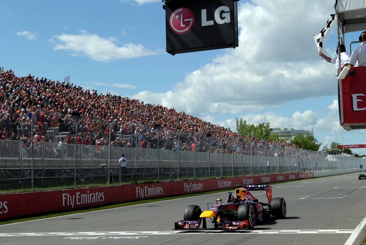 (CORRECTION-IPTC-BYLINE) Red Bull driver Sebastian Vettel of Germany takes the checkered flag to win the Canadian Formula One Grand Prix at the Circuit Gilles Villeneuve in Montreal on June 9, 2013.   AFP PHOTO/Stan HONDASTAN HONDA/AFP/Getty Images
