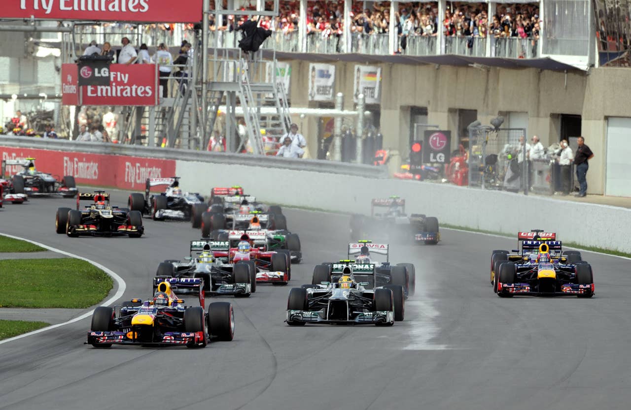 Red Bull driver Sebastian Vettel of Germany (L) leads the grid into the first turn at the start of the Canadian Formula One Grand Prix at the Circuit Gilles Villeneuve in Montreal on June 9, 2013.   AFP PHOTO/Stan HONDASTAN HONDA/AFP/Getty Images