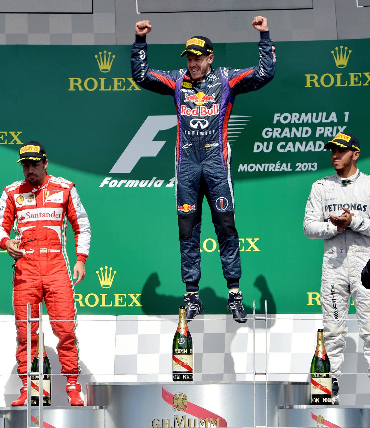 (CORRECTION-IPTC-BYLINE) Red Bull driver Sebastian Vettel of Germany (C) jumps on the podium after winning the Canadian Formula One Grand Prix at the Circuit Gilles Villeneuve in Montreal on June 9, 2013. Ferrari driver Fernando Alonso of Spain (L) finished second and Mercedes driver Lewis Hamilton of Britain (R) finished third.    AFP PHOTO/Stan HONDASTAN HONDA/AFP/Getty Images