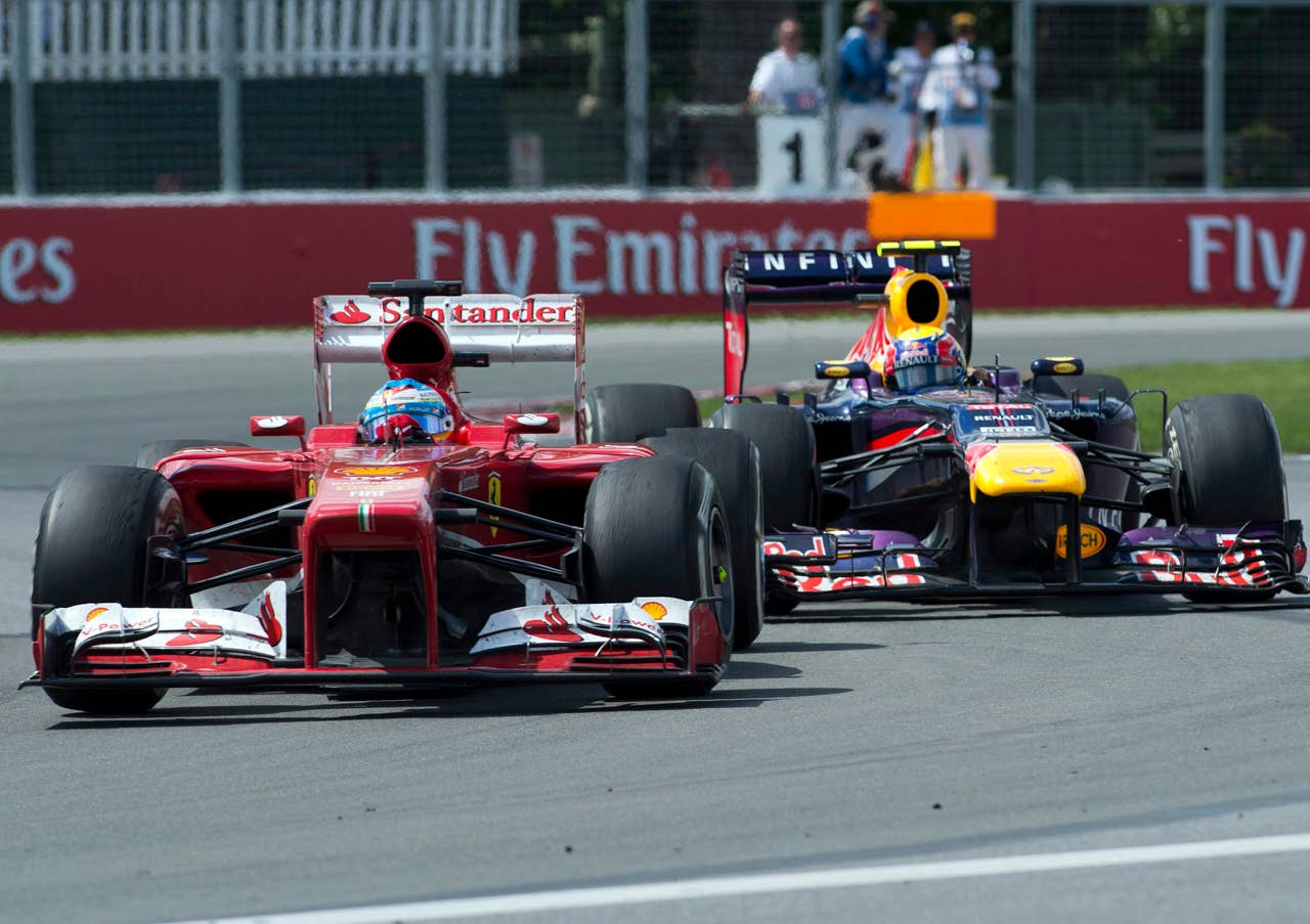 Ferrari driver Fernando Alonso of Spain, left, passes Red Bull driver Mark Webber of Australia in the Senna corner during the Canadian Grand Prix, Sunday, June 9, 2013 in Montreal.  (AP Photo/The Canadian Press, Ryan Remiorz)