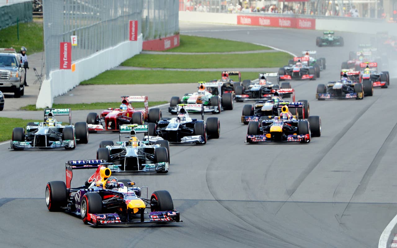 Red Bull driver Sebastian Vettel of Germany (L) leads the grid into the first turn at the start of the Canadian Formula One Grand Prix at the Circuit Gilles Villeneuve in Montreal on June 9, 2013. AFP PHOTO/Stan HONDASTAN HONDA/AFP/Getty Images