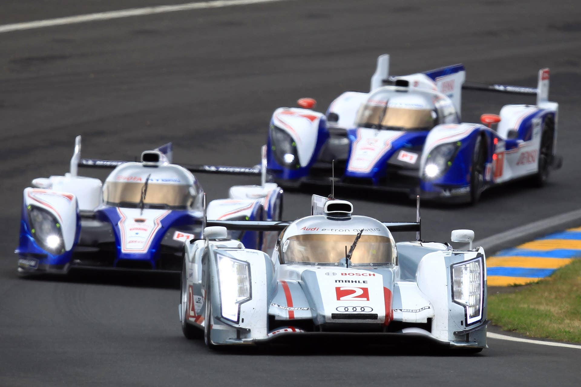 The Audi R18 E-Tron n2 driven by Allan McNish of Scotland, Rinaldo Capello of Italy and Tom Kristensen of Denmark powers his car in a curve ahead of the Toyota n8 and the Toyota n7 during the first lap of the 80th 24-hour Le Mans endurance race, in Le Mans, western France, Saturday, June 16, 2012. (AP Photo/David Vincent)