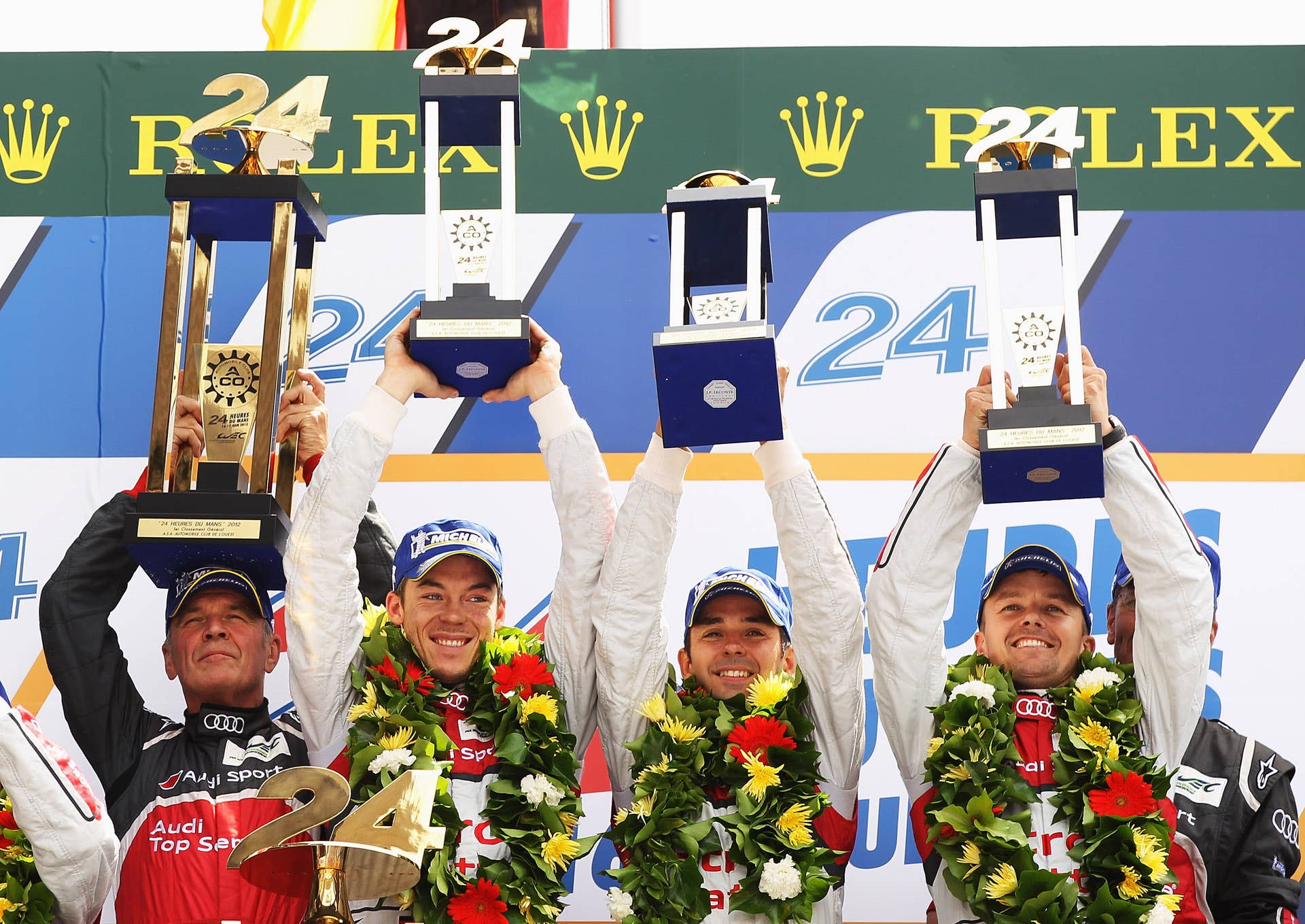 LE MANS, FRANCE - JUNE 17: The Audi Sport Team Joest R18 E-Tron Quattro of Andre Lotterer (2nd L), Benoit Treluyer (2nd R) and Marcel Fassler (R) celebrate with Head of Audi Sport Dr Wolfgang Ullrich (L) after winning the Le Mans 24 Hour race at the Circuit de la Sarthe on June 16, 2012 in Le Mans, France. (Photo by Bryn Lennon/Getty Images)