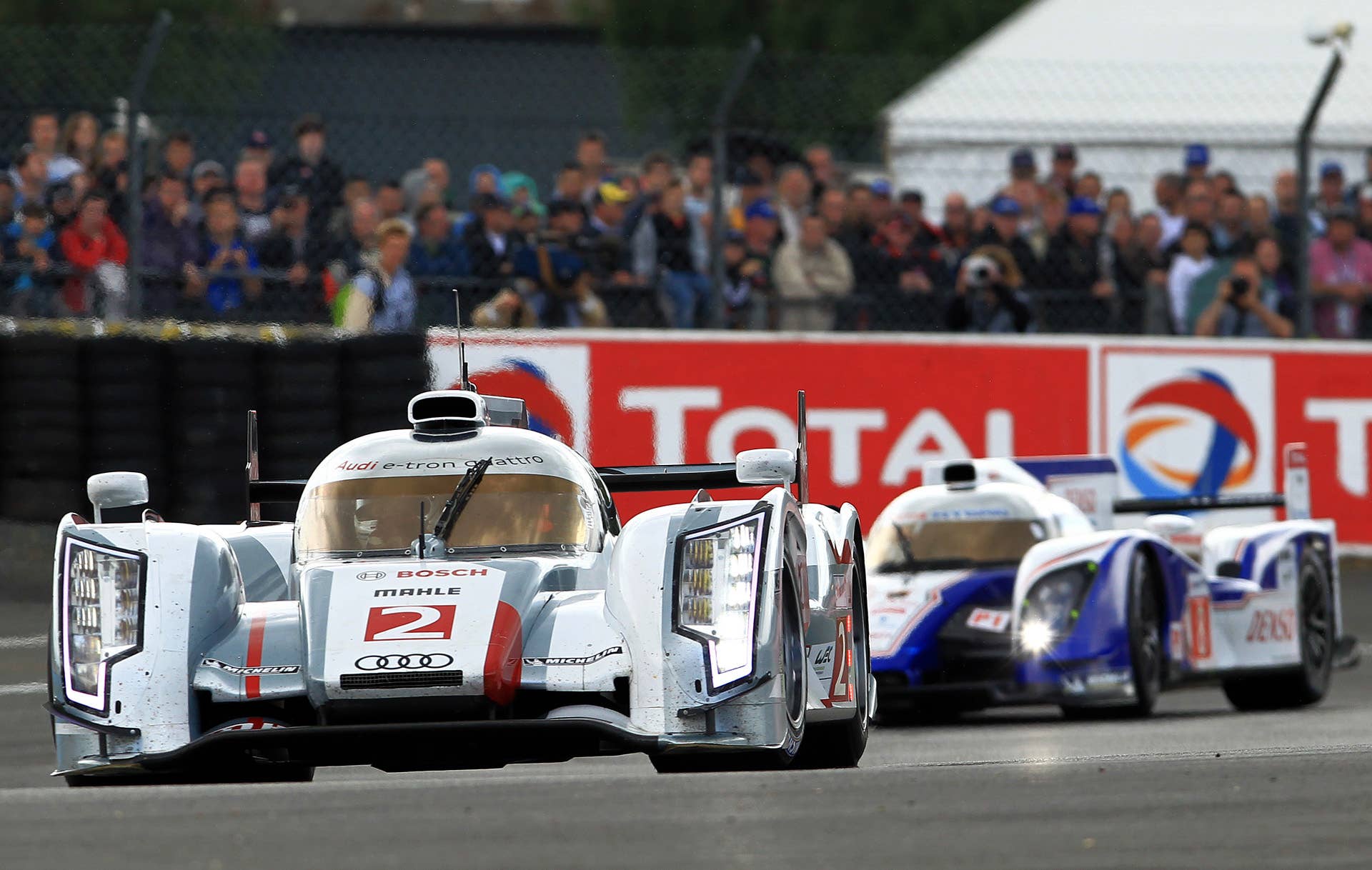 The Audi R18 TDI No2 driven by Allan Mac Nish of Scotland, foreground, and the Toyota TS030 Hybrid No8 driven by Stephane Sarrazin of France steers their car in a curve during the 80th 24-hour Le Mans endurance race, in Le Mans, western France, Saturday, June 16, 2012. (AP Photo/Bob Edme)