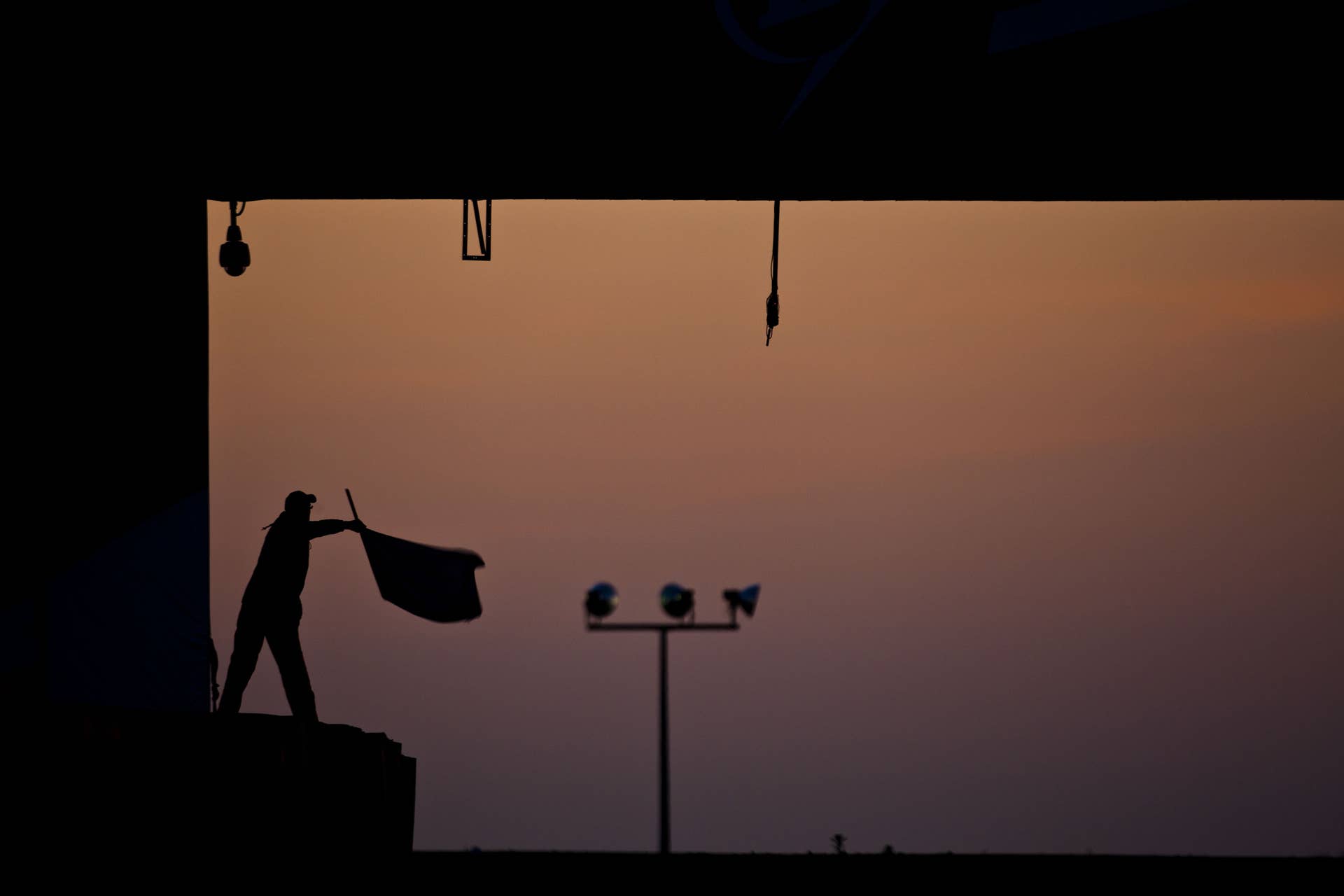 LE MANS, FRANCE - JUNE 17: A marshal waves a flag at sunrise during the field before the Le Mans 24 Hour race at the Circuit des 24 Heures du Mans on June 16, 2012 in Le Mans, France (Photo by Drew Gibson/Getty Images)