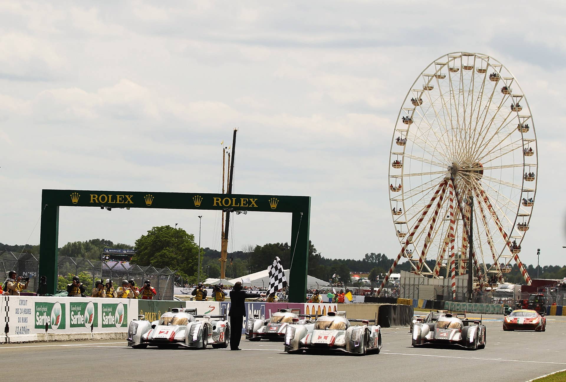 LE MANS, FRANCE - JUNE 17: The winning car Audi Sport Team Joest R18 E-Tron Quattro (front right No.1) of Andre Lotterer, Marcel Fassler and Benoit Treluyer cross the finishing line at the end of the Le Mans 24 Hour race at the Circuit de la Sarthe on June 16, 2012 in Le Mans, France. (Photo by Bryn Lennon/Getty Images)