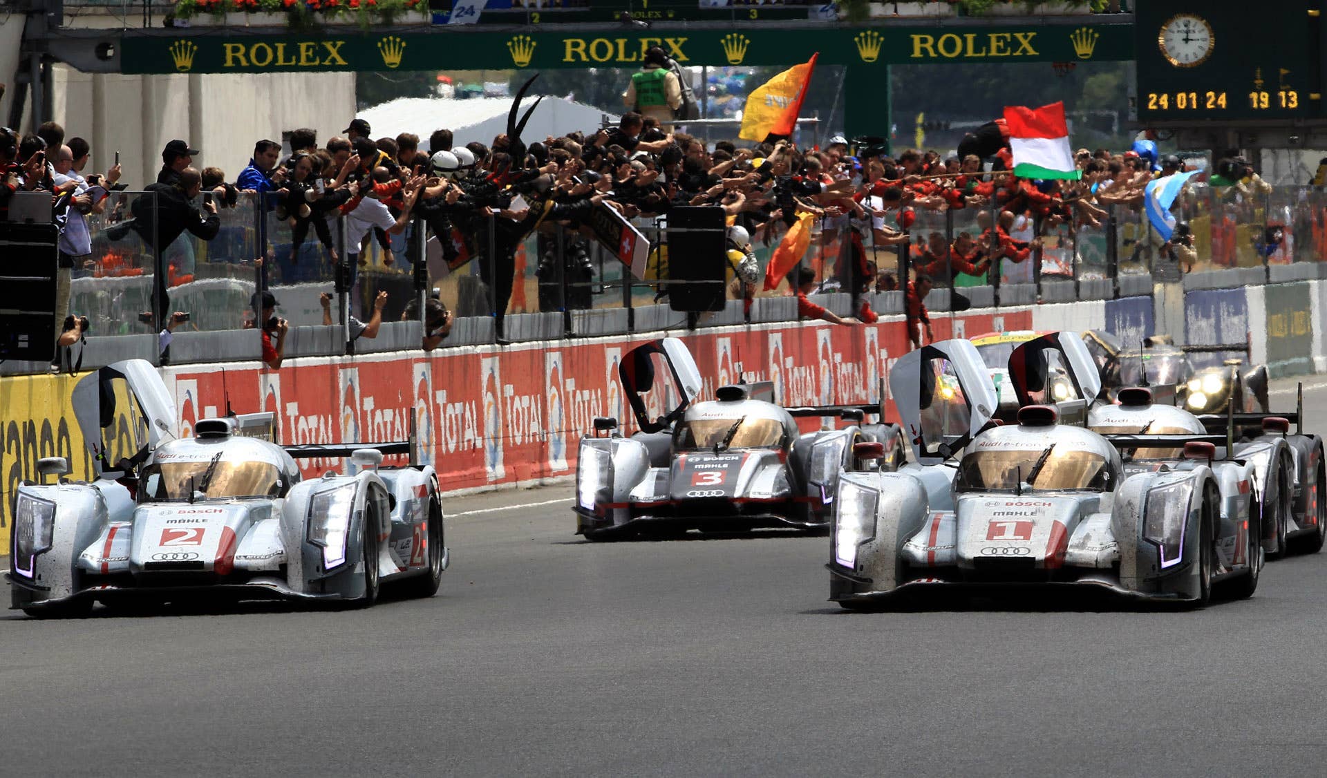 The four Audi R18 cars jubilate their win of the 80th 24 hours Le Mans endurance race in Le Mans, western France, Sunday, June 17, 2012, with cars from left, No 1 driven by Andre Lotterrer od Germany and No.2 drivenTom Kristensen of Denmark No.3 driven by Loic Duval of France and No4 driven by Mike Rickenfeller of Germany. Audi won the 24 Hours of Le Mans for the eleventh time on Sunday. (AP Photo/Bob Edme)