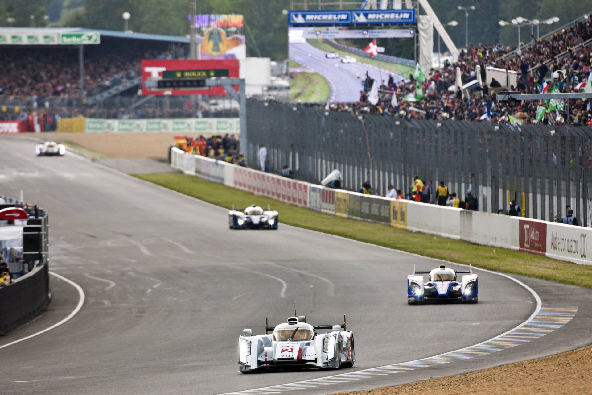 LE MANS, FRANCE - JUNE 16:  The Audi Sport Team Joest Audi R18 e-tron quattro hybrid driven by Allan McNish of Scotland, Tom Kristensen of Denmark, Dindo Capello of Italy leads The Toyota Racing Toyota TS 030 - Hybrid driven by Anthony Davidson of England, Sebastien Buemi of Switzerland and Stephane Sarrazin of France during the Le Mans 24 Hour race at the Circuit des 24 Heures du Mans on June 16, 2012 in Le Mans, France  (Photo by Drew Gibson/Getty Images)