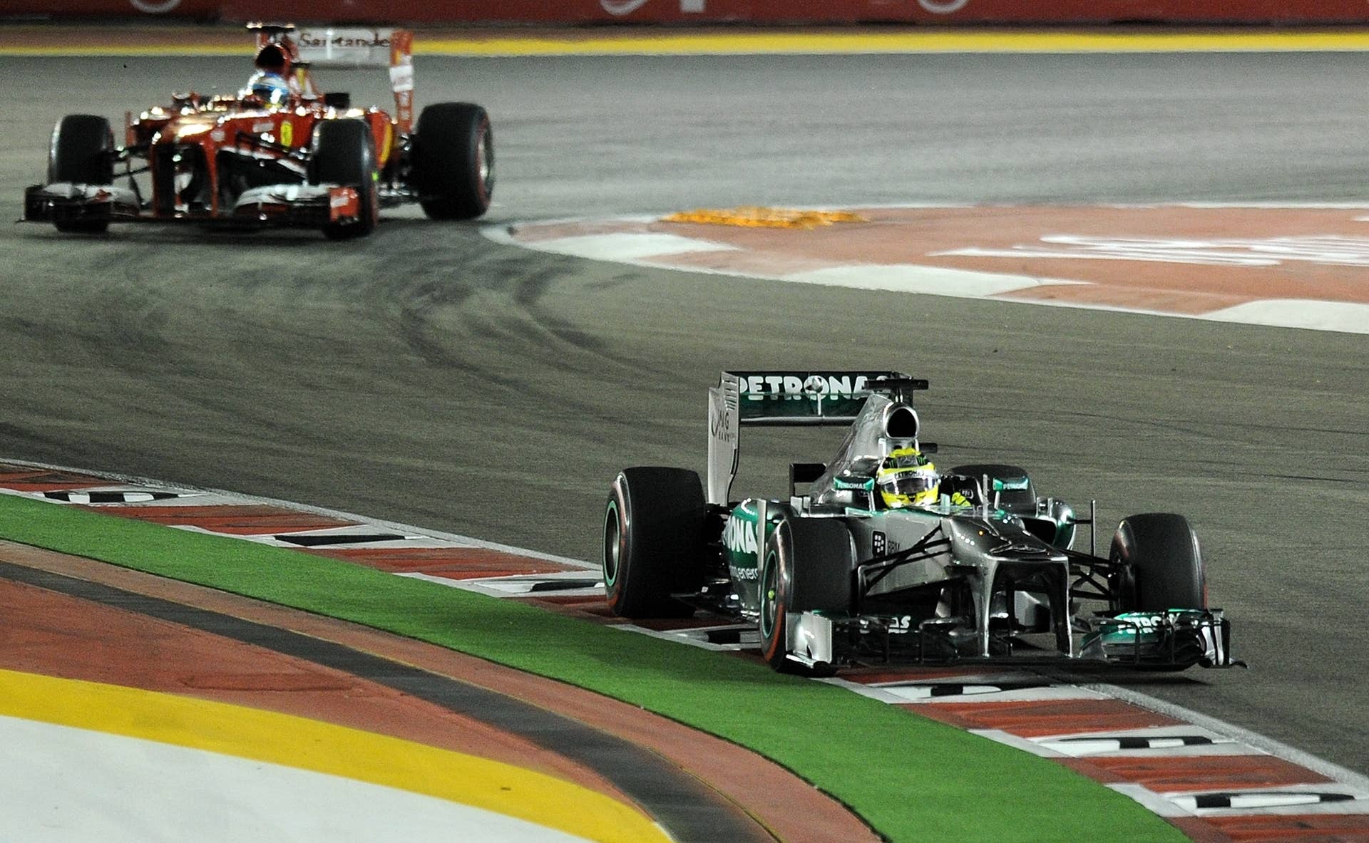 Mercedes driver Nico Rosberg of Germany (R) drives ahead of Ferrari driver Fernando Alonso of Spain (L) during the Formula One Singapore Grand Prix on September 22, 2013.   AFP PHOTO /  MANAN VATSYAYANA        (Photo credit should read MANAN VATSYAYANA/AFP/Getty Images)