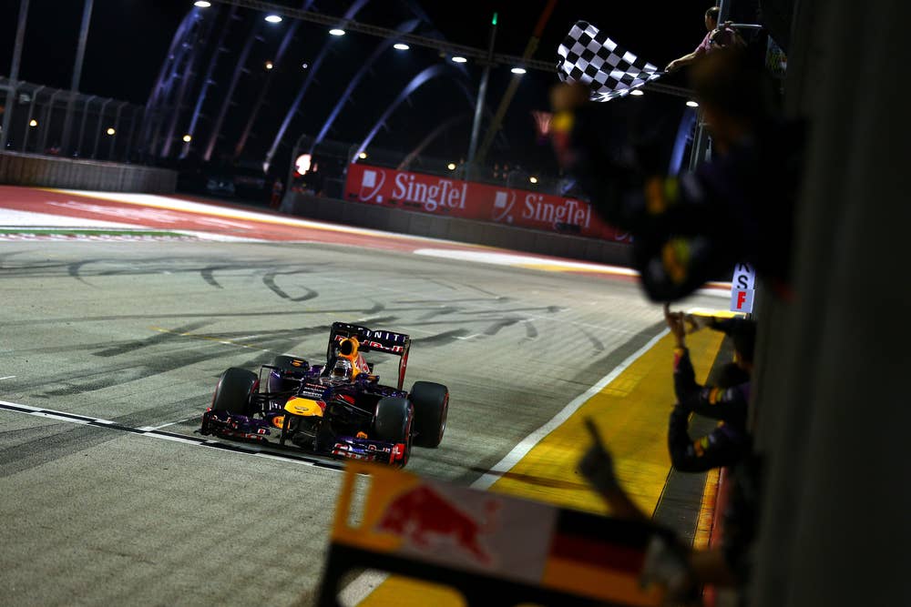SINGAPORE - SEPTEMBER 22:  Sebastian Vettel of Germany and Infiniti Red Bull takes the chequered flag and victory during the Singapore Formula One Grand Prix at Marina Bay Street Circuit on September 22, 2013 in Singapore, Singapore.  (Photo by Paul Gilham/Getty Images)
