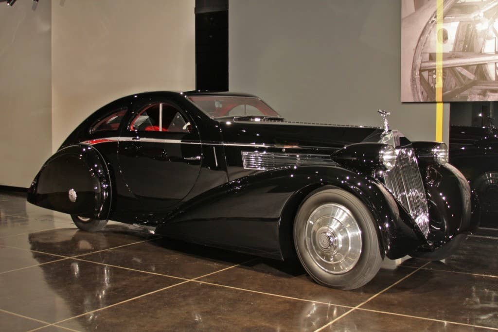 The exotic“Round Door” Rolls-Royce was delivered new in 1925 with a Hooper Cabriolet body to its first owner, a Mrs. Hugh Dillman of Detroit.  It appears never to have left England and was re-sold when still virtually new to the Raja of Nanpara.  In about 1934 a subsequent owner sent the car to Jonckheere of Belgium to be fitted with fashionably aerodynamic coachwork complete with twin sunroofs, round doors, a large fin, and a sloping radiator shell.  Once thought to have been owned by the Duke of Windsor, the concours-winning car then passed through the hands of several other owners before being discovered in New Jersey in the early-1950s in near derelict condition.  Max Obie later acquired the unusual Rolls-Royce, had it painted gold, and charged curious individuals one dollar to enter a special enclosure to look at the car.  The Phantom I then spent time on the East Coast of the United States and in Japan before coming into the possession of the Petersen Automotive Museum in the spring of 2001.