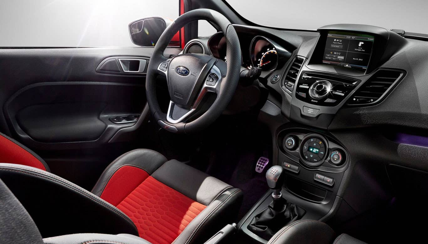 Because the Fiesta ST costs less than $25,000, the cabin isn't overly luxurious. The designers, however, have done a good job working with that price, using paints and accents that suggest that the car is more premium that it really is. Sure, the interior uses a lot of plastic, but the glossy black paint renders it mostly inoffensive.  It's not the quietest subcompact, but that's actually a good thing. In fact, it's by design. The car employs Ford's Sound Symposer technology, which pumps engine noise into the cabin through a hole in the firewall. The deep, throaty exhaust note is something you definitely want to hear when you're driving. It really adds to the experience, although you may find the drone to get a little tiring over long distances.  The center stack has been updated for all the Fiestas for 2014, and it is a much more user friendly experience. There are still a lot of buttons to contend with, but once you've learned the layout, the radio and heating and cooling knobs are easy to locate and operate.  The big problem with the interior is the seats. My tester had the optional Recaro package, which included special racing bucket seats. They're great for throwing the car around on curvy roads, but are just awful on long trips. Because they're small and super firm, spending more than an hour in them is  quite uncomfortable.  Research the Ford Fiesta ST Ford Fiesta ST Overview Ford Fiesta ST Photos & Video Ford Fiesta ST Local Dealer Price Quote