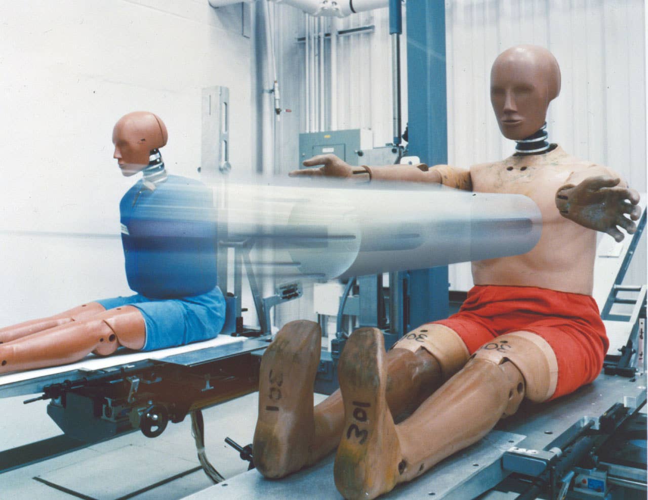 A"Hybrid III" front-impact dummy undergoes testing with a dropping pendulum to calibrate it's instrumentation. Another type of dummy(left) is used for side-impact testing. (03/31/2011)