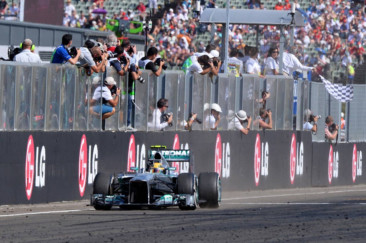 Mercedes'  British driver Lewis Hamilton celebrates winning as he passes the checkered flag at the Hungaroring circuit in Budapest on July 28, 2013 after the Hungarian Formula One Grand Prix.     AFP PHOTO / ATTILA KISBENEDEKATTILA KISBENEDEK/AFP/Getty Images