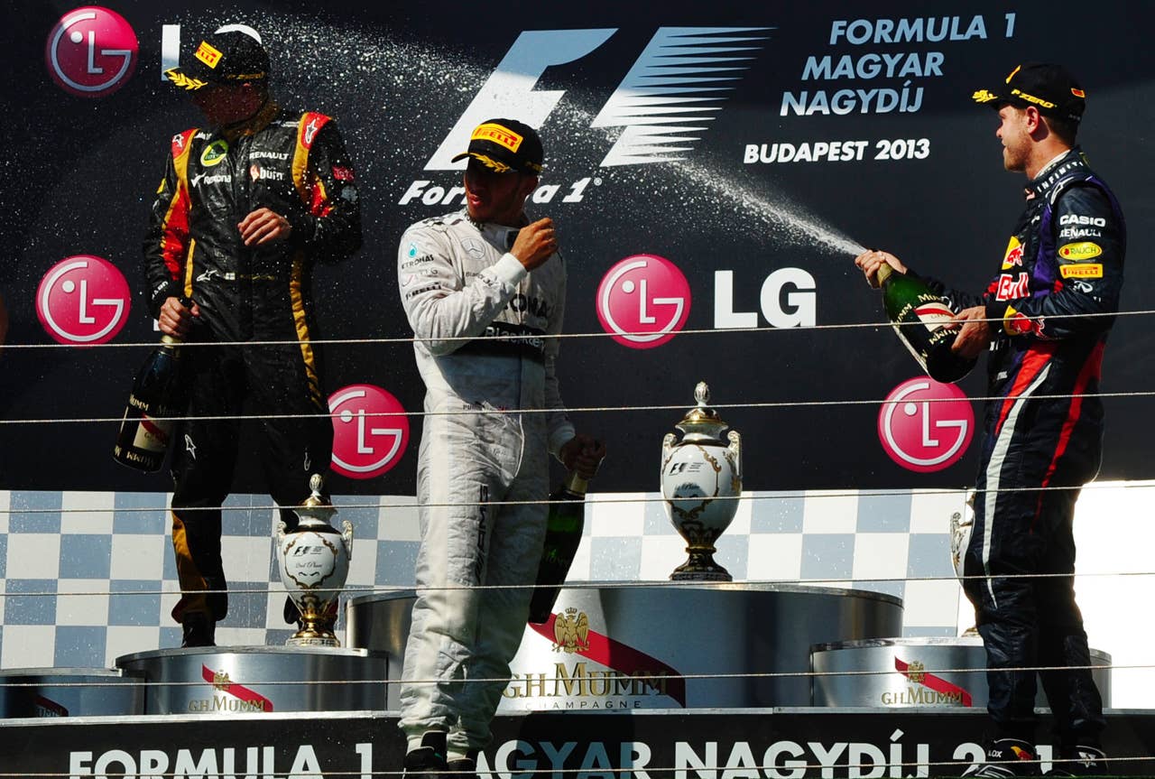 (L to R) Lotus F1 Team's Finnish driver Kimi Raikkonen, British driver Lewis Hamilton and Red Bull Racing's German driver Sebastian Vettel celebrate on the podium at the Hungaroring circuit in Budapest on July 28, 2013 after the Hungarian Formula One Grand Prix.   AFP PHOTO / TOM GANDOLFINITom Gandolfini/AFP/Getty Images