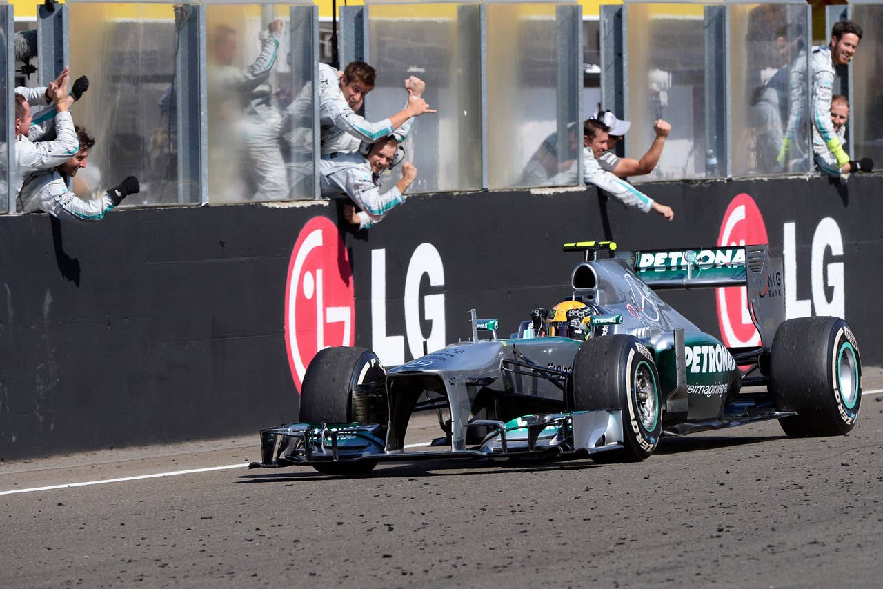 TOPSHOTS Mercedes'  British driver Lewis Hamilton celebrates winning as he passes teammates at the Hungaroring circuit in Budapest on July 28, 2013 after the Hungarian Formula One Grand Prix.     AFP PHOTO / ATTILA KISBENEDEKATTILA KISBENEDEK/AFP/Getty Images