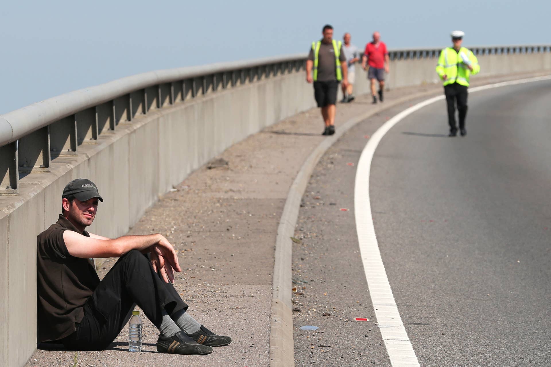 ISLE OF SHEPPEY, KENT - SEPTEMBER 05:  A driver waits on the pavement for his vehicle to be recovered at the site of a major traffic accident on the A249 Sheppey crossing bridge in Kent on September 5, 2013 in Isle of Sheppey, Kent. Over 130 vehicles were involved in the series of accidents, with thick fog blamed for poor visibility. The crash occurred around 07:15AM BST, with at least 8 people suffering serious injuries, and approximately 60 people treated for minor injuries.  (Photo by Peter Macdiarmid/Getty Images)