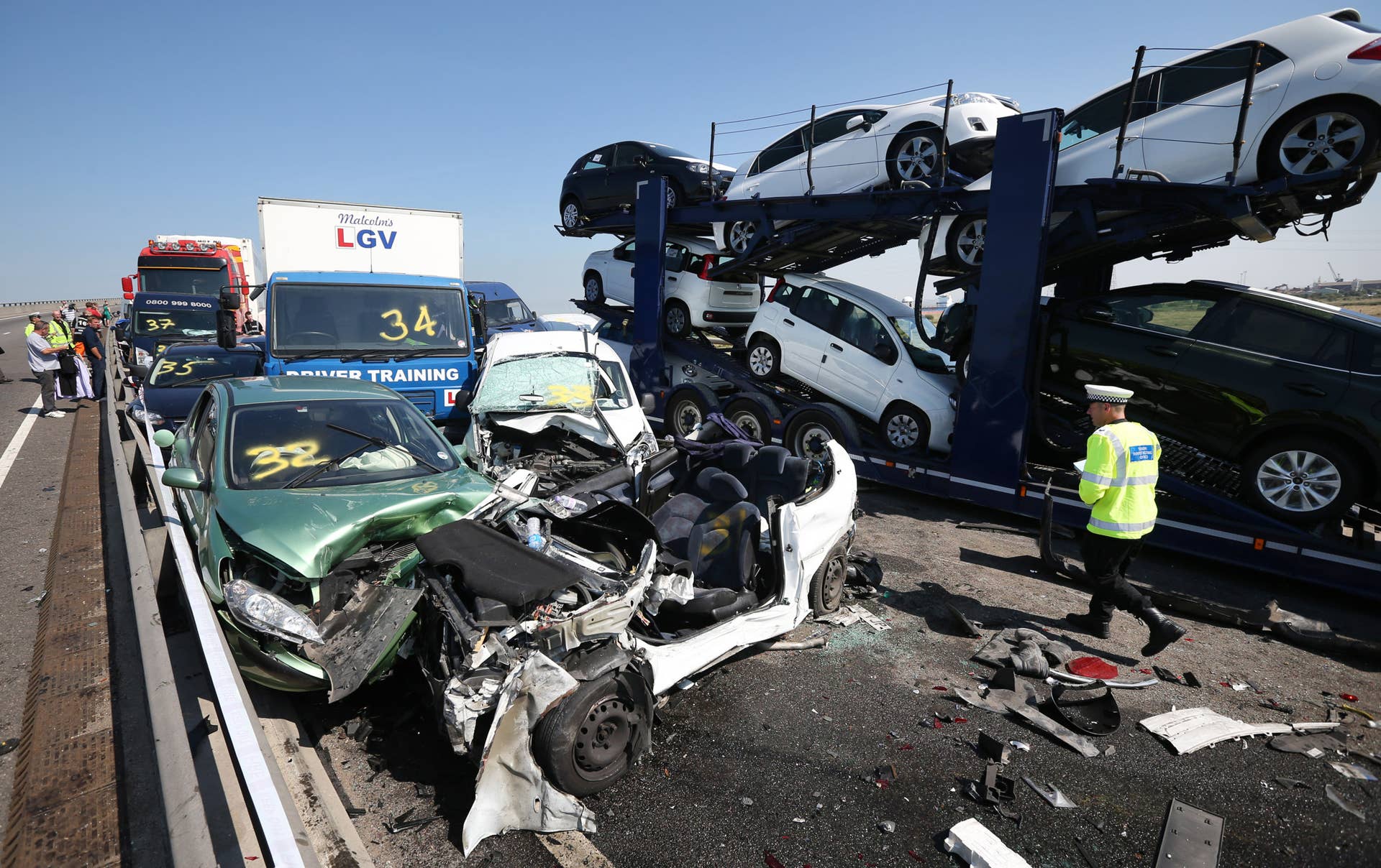 ISLE OF SHEPPEY, KENT - SEPTEMBER 05:  A policeman inspects the site of a major traffic accident on the A249 Sheppey crossing bridge in Kent on September 5, 2013 in Isle of Sheppey, Kent. Over 130 vehicles were involved in the series of accidents, with thick fog blamed for poor visibility. The crash occurred around 07:15AM BST, with at least 8 people suffering serious injuries, and approximately 60 people treated for minor injuries.  (Photo by Peter Macdiarmid/Getty Images)