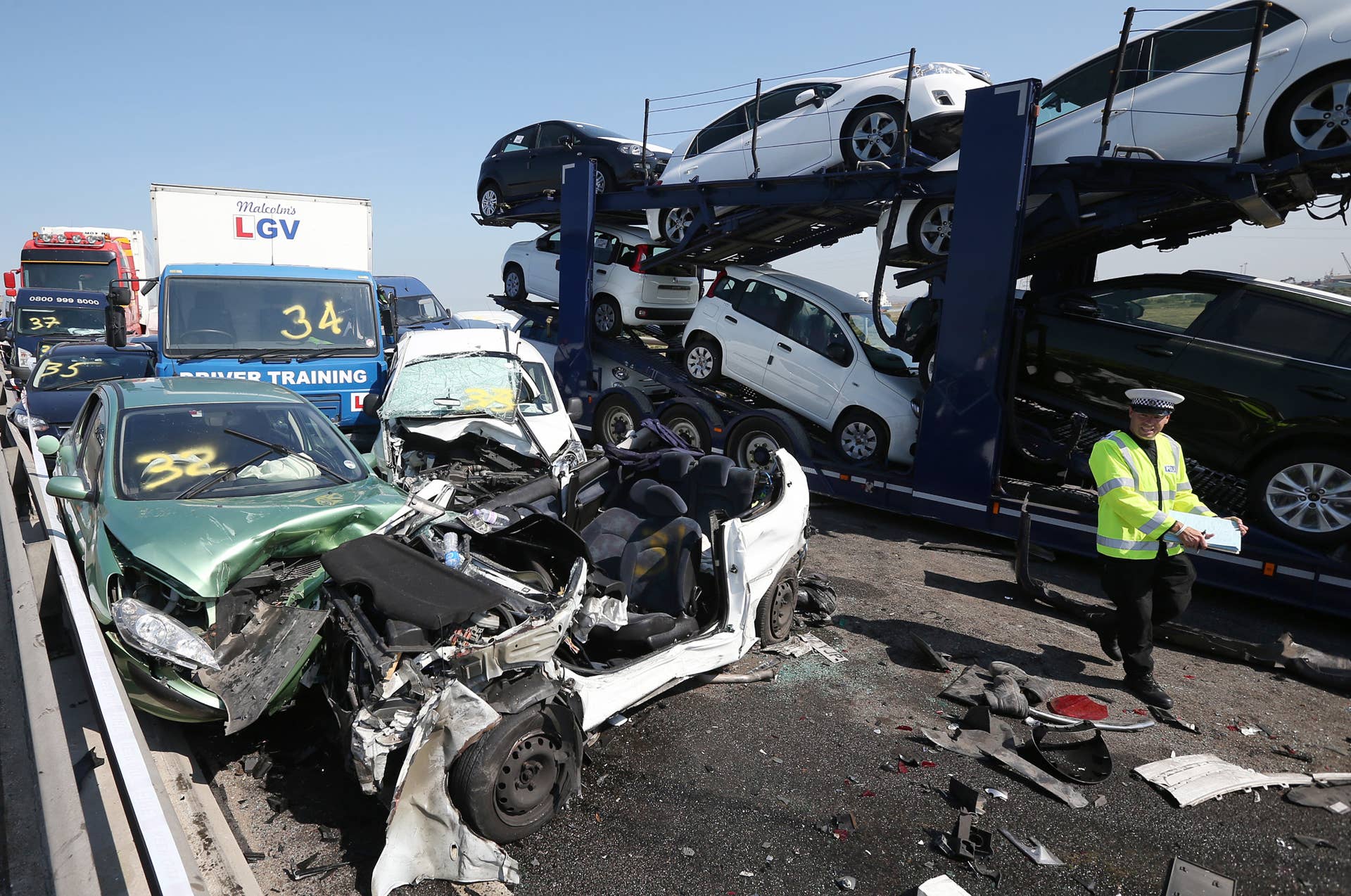 ISLE OF SHEPPEY, KENT - SEPTEMBER 05:  A policeman inspects the site of a major traffic accident on the A249 Sheppey crossing bridge in Kent on September 5, 2013 in Isle of Sheppey, Kent. Over 130 vehicles were involved in the series of accidents, with thick fog blamed for poor visibility. The crash occurred around 07:15AM BST, with at least 8 people suffering serious injuries, and approximately 60 people treated for minor injuries.  (Photo by Peter Macdiarmid/Getty Images)